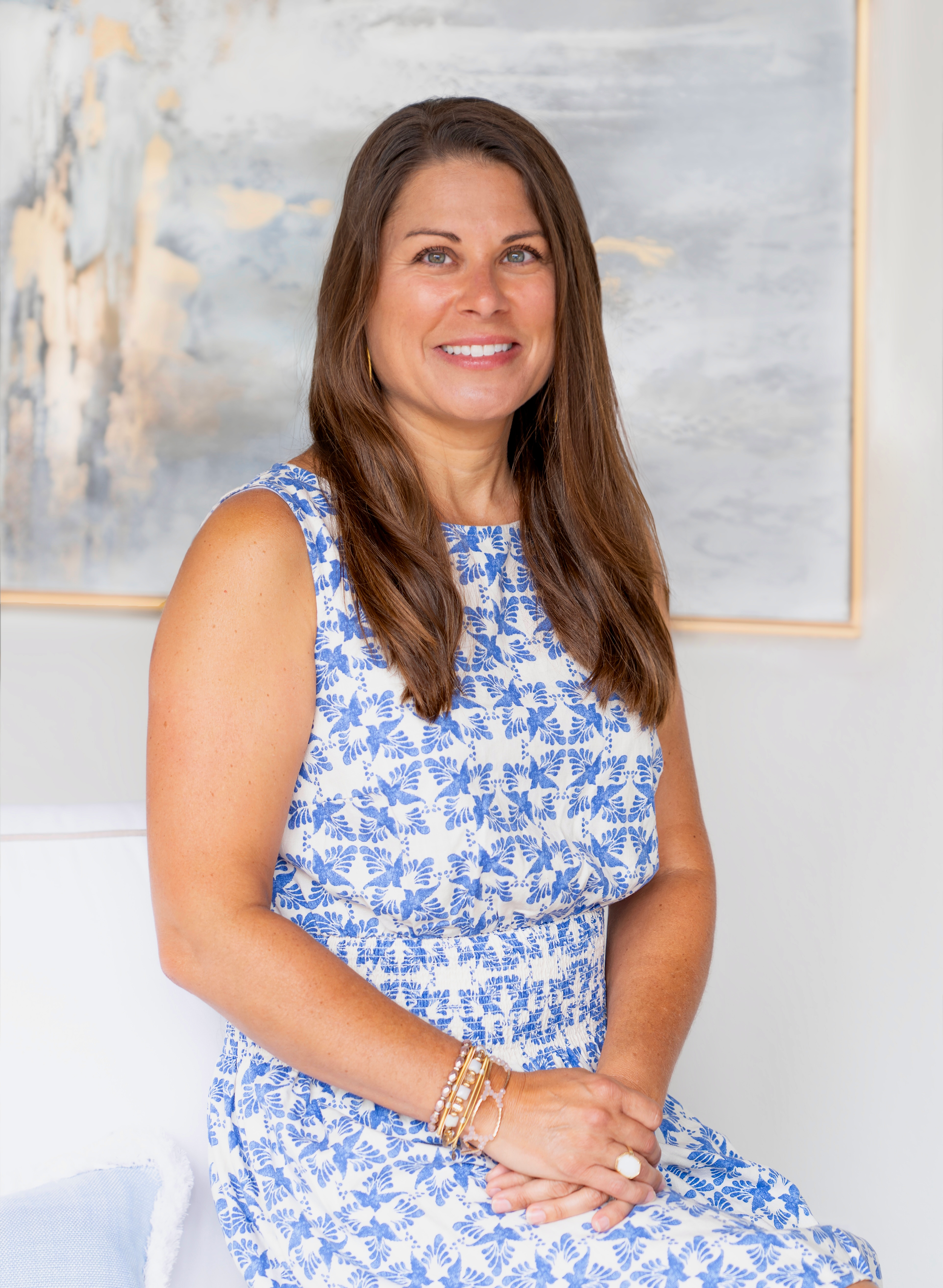 Abby Robb sitting indoors against a white wall with abstract art in the background.