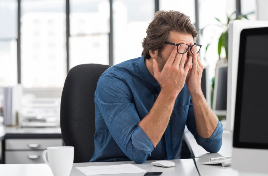 Frustrated small business owner with his head in his hands and sitting in front of a computer.