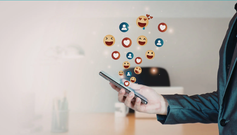 Closeup of a man's hand holding a cell phone with reaction buttons coming from the phone