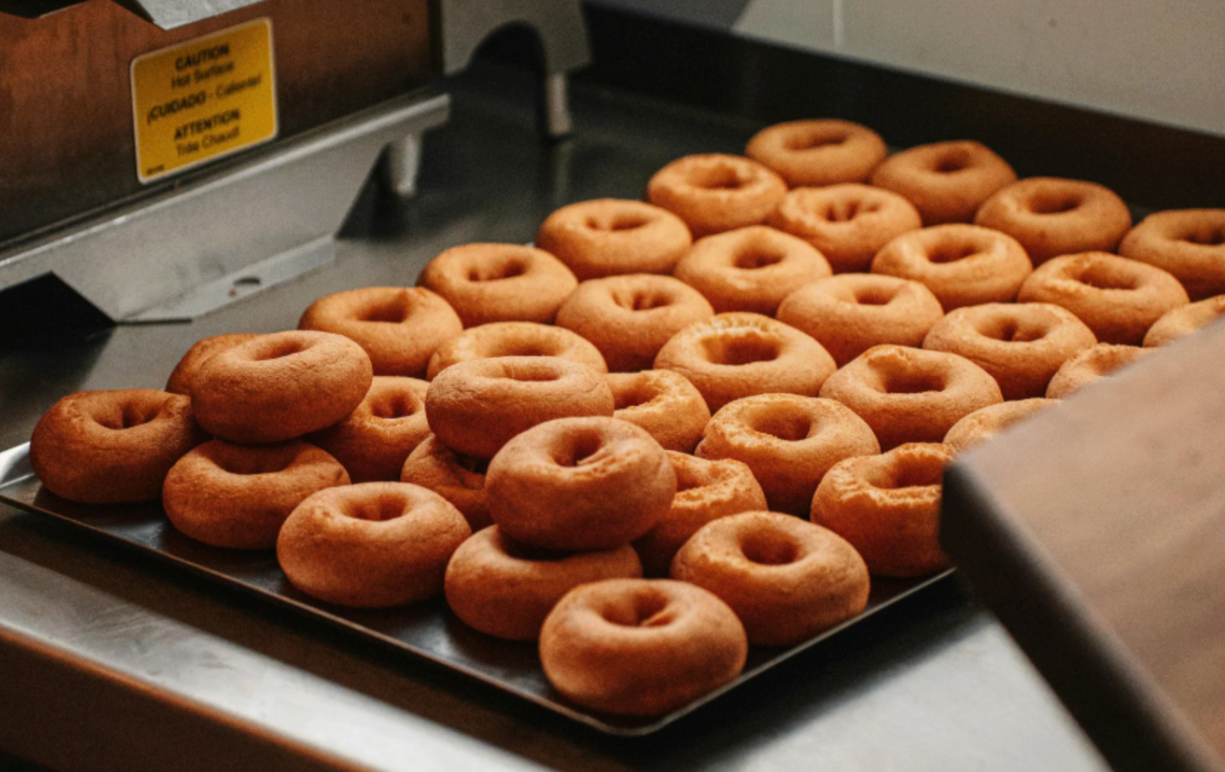 Fresh donuts out of the fryer sitting on a tray