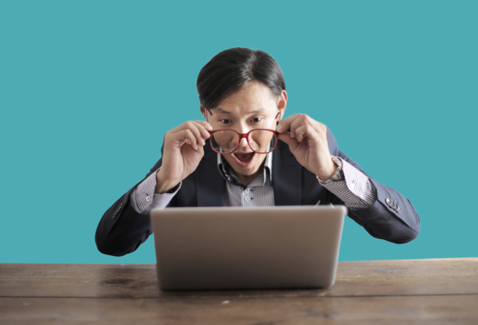 surprised man looking at a laptop and pulling his glasses off