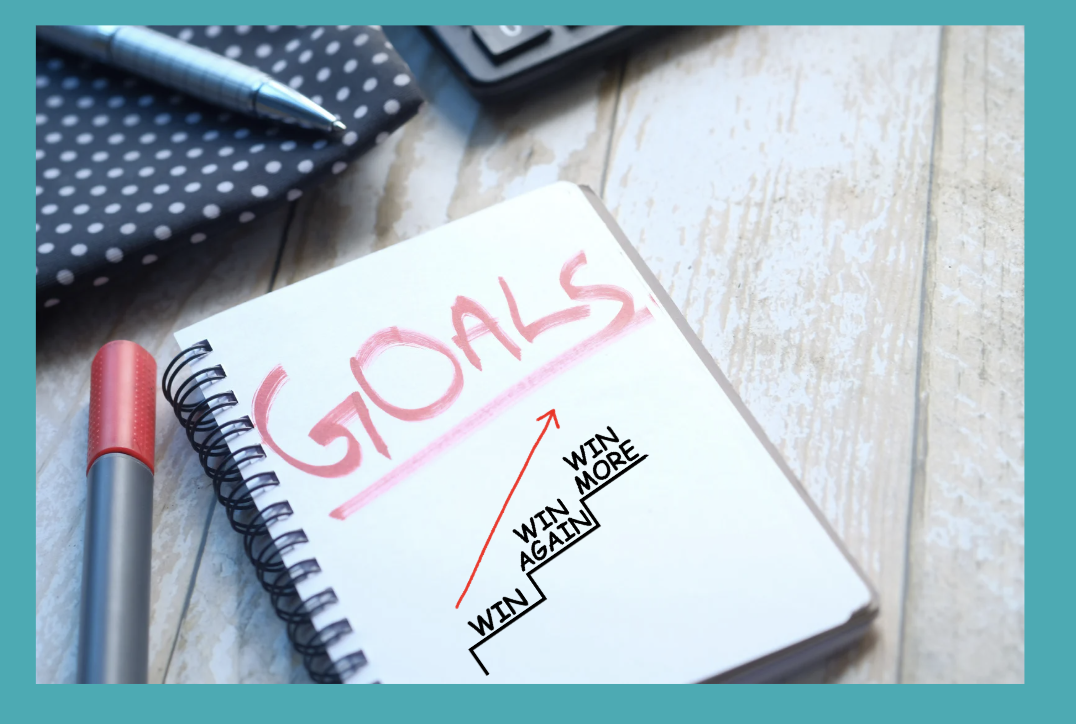 Note pad with the word "Goals" and then a note that says "win, win again, win more."