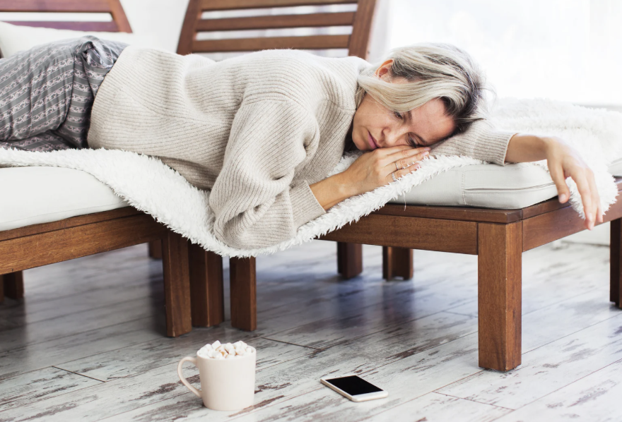 Bored woman laying on a couch and staring at her phone on the floor while the website loads