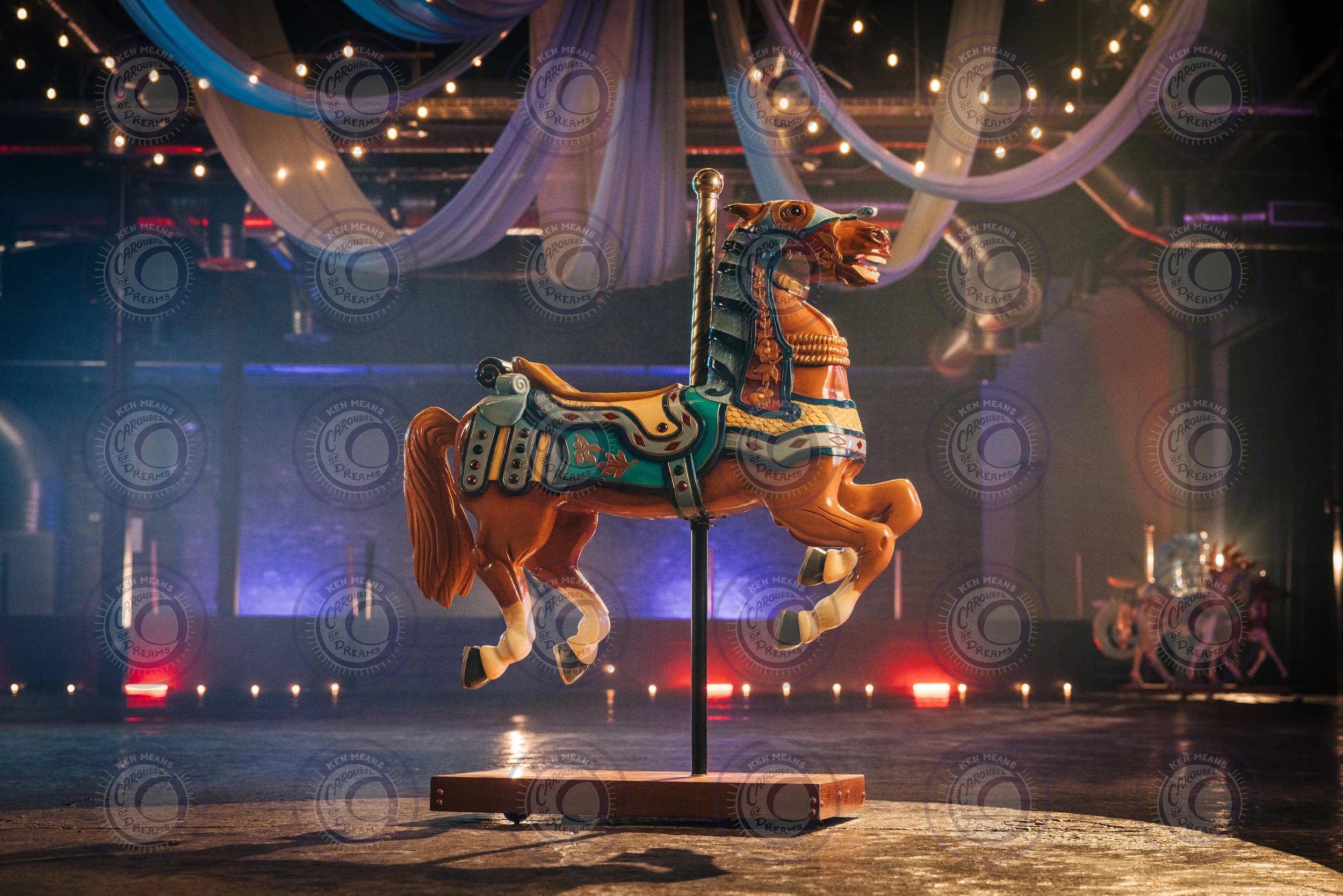Colorful carousel horse in a dimly lit room with draped fabric and string lights overhead.