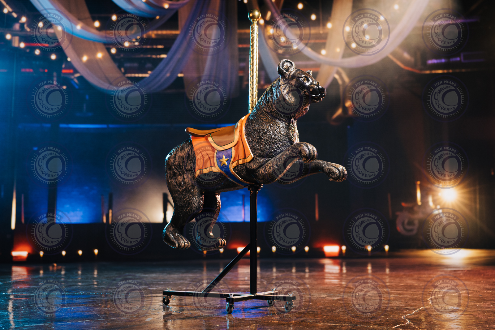 Carousel dog figure on a stand in a dimly lit room, surrounded by draped fabric and string lights.