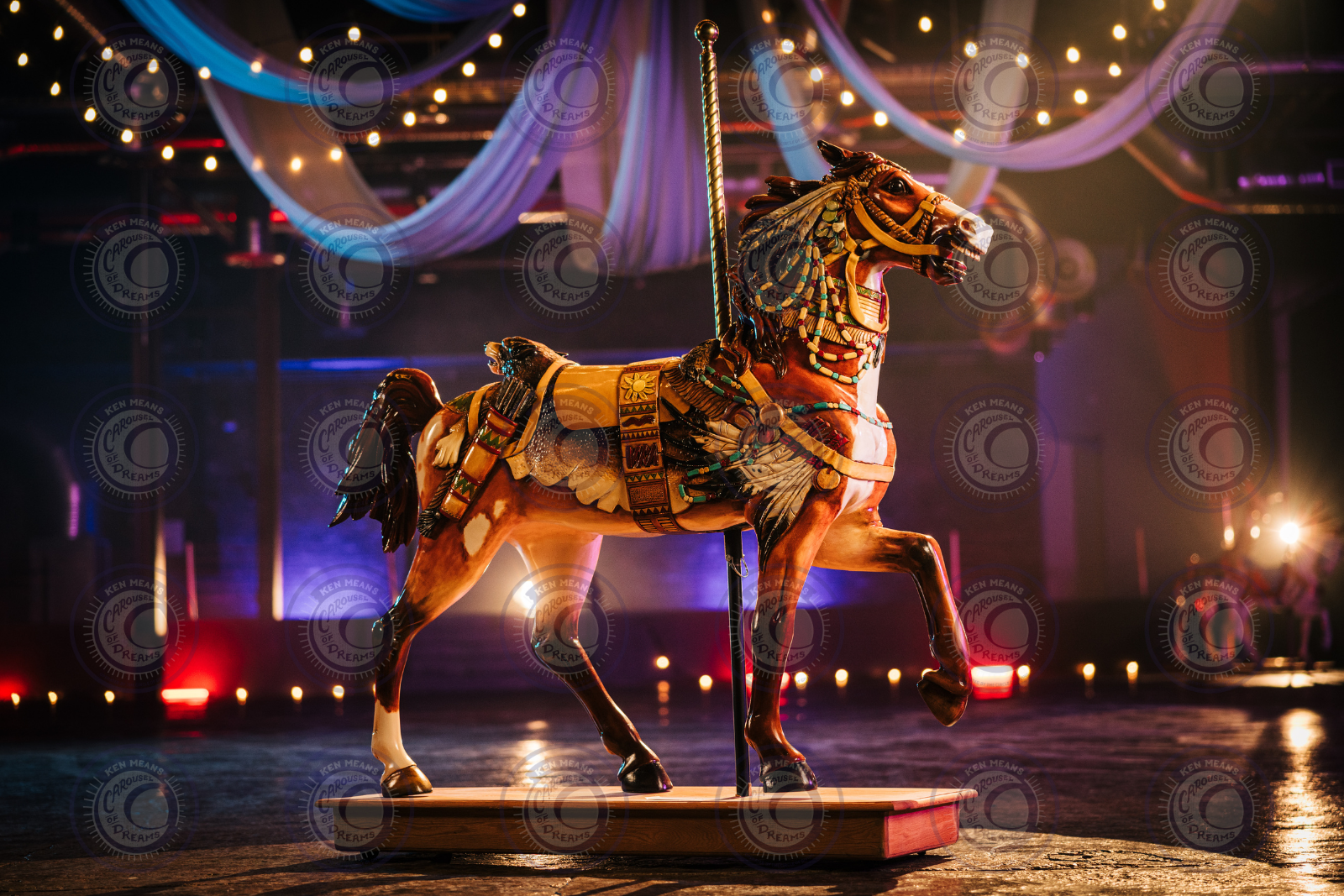 Ornate carousel horse on display with draped fabric and lights