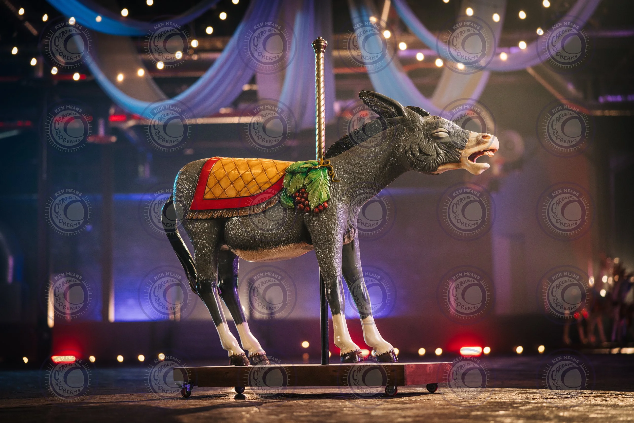 A carousel donkey with decorative elements in a lit indoor setting.