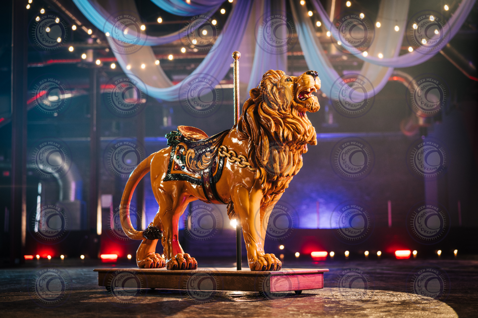 Carousel lion figure with decorative saddle and lights in a circus-themed setting.