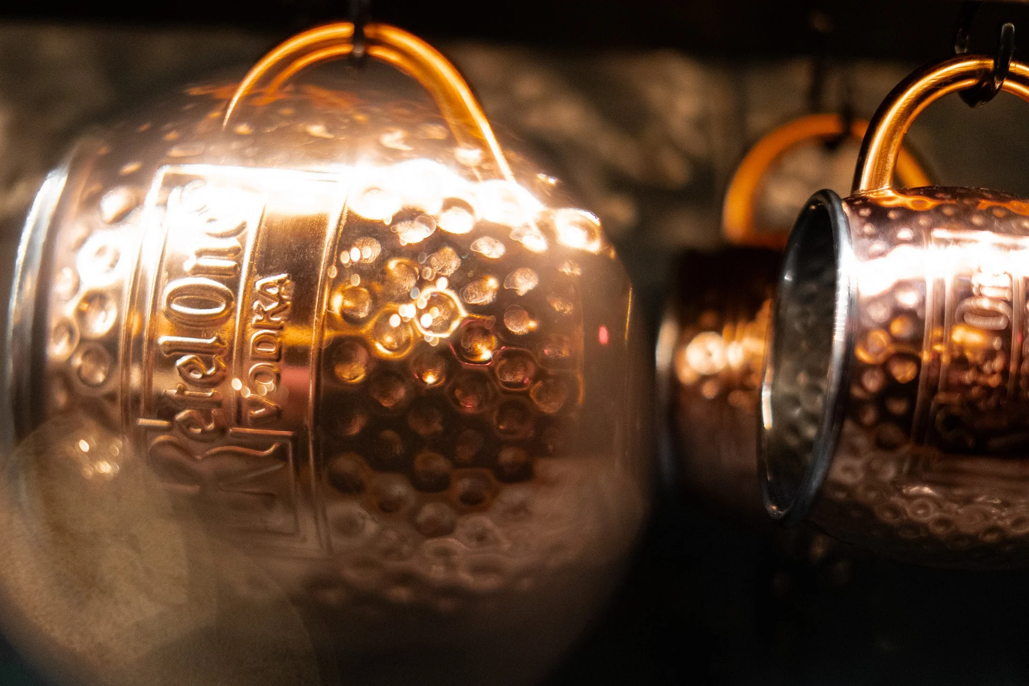 Close-up of vintage copper lanterns with the brand name 'Raylite' embossed on them, hanging in a dark space.
