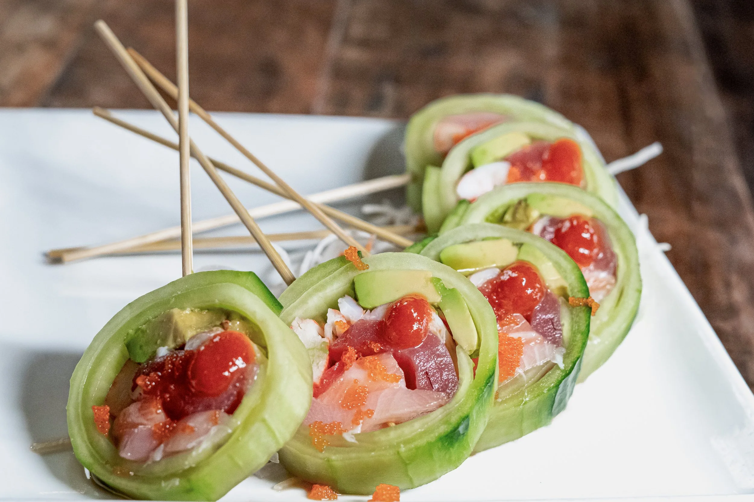 Cucumber slices stuffed with raw fish, topped with red sauce, served on skewers.
