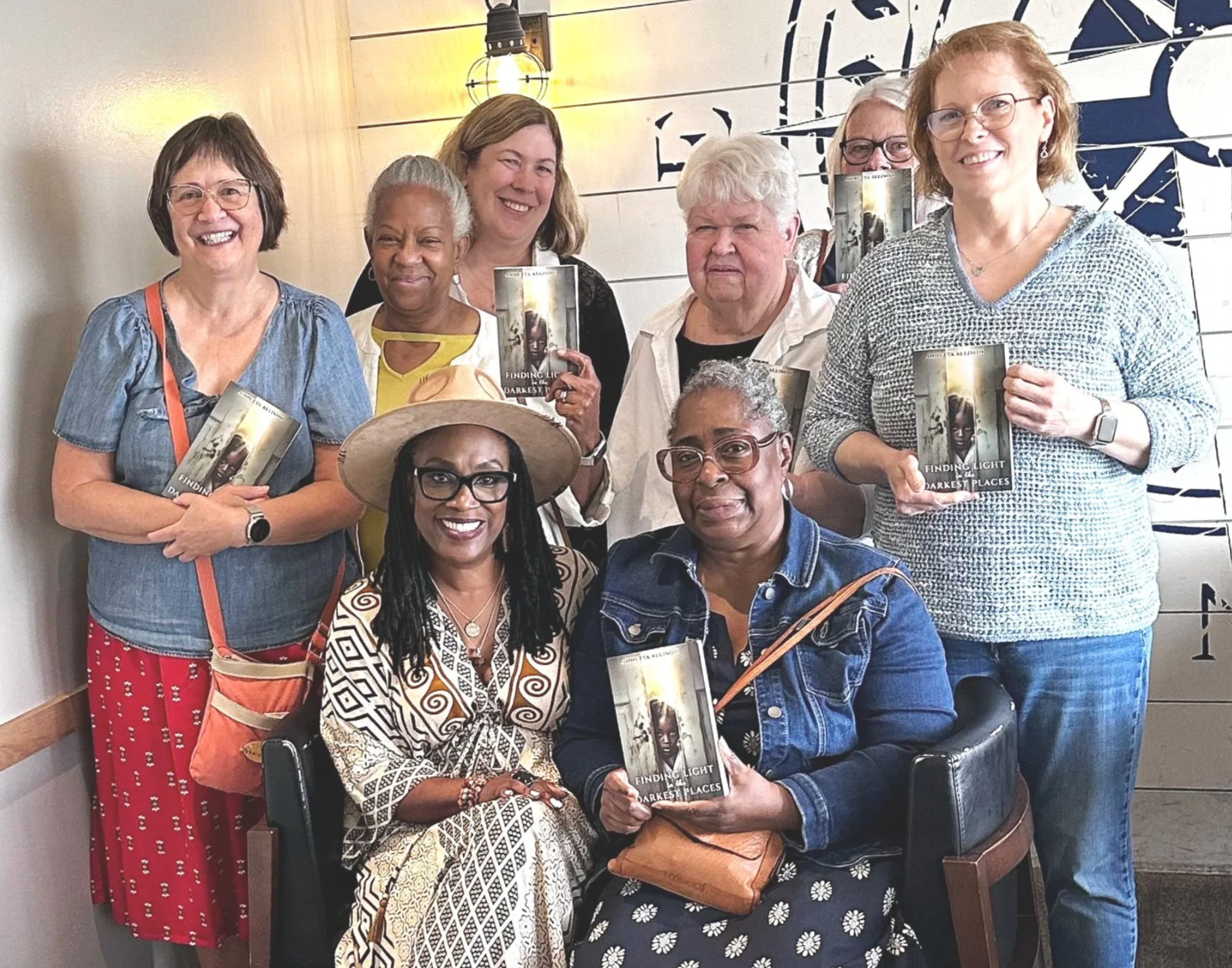 Annetta Allison posing with several women who are holding copies of her book and smiling at the camera.
