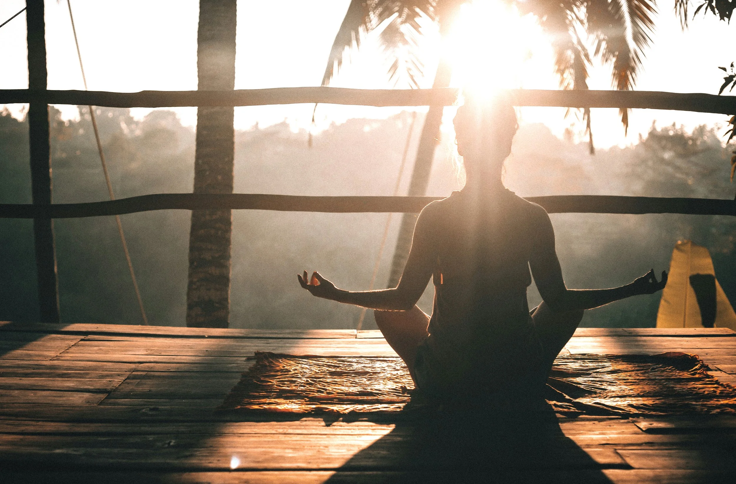 woman meditating at sunrise in a rustic tropical location