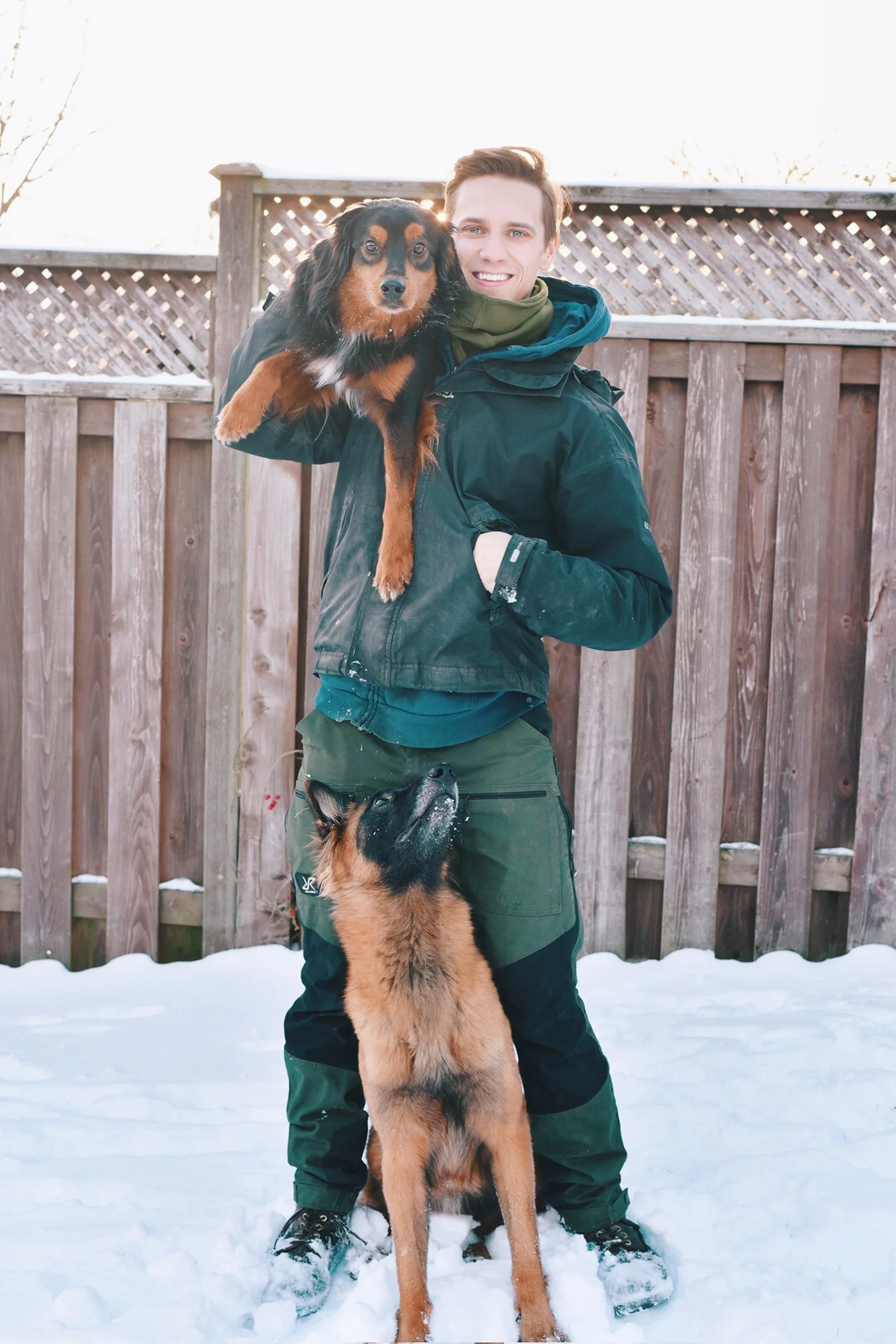 Dog trainer with dog on shoulder and dog between legs