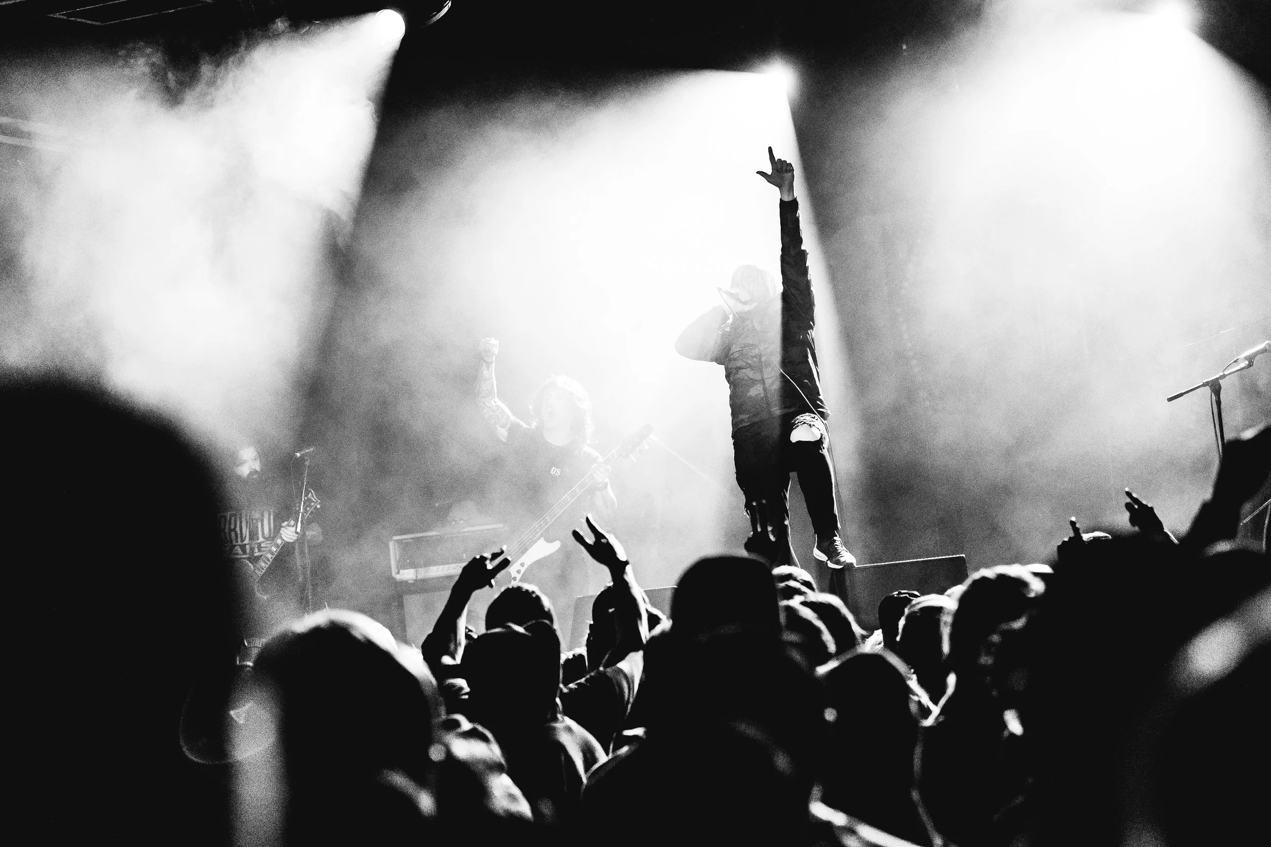 Musician performing on stage with crowd in front, black and white photo.