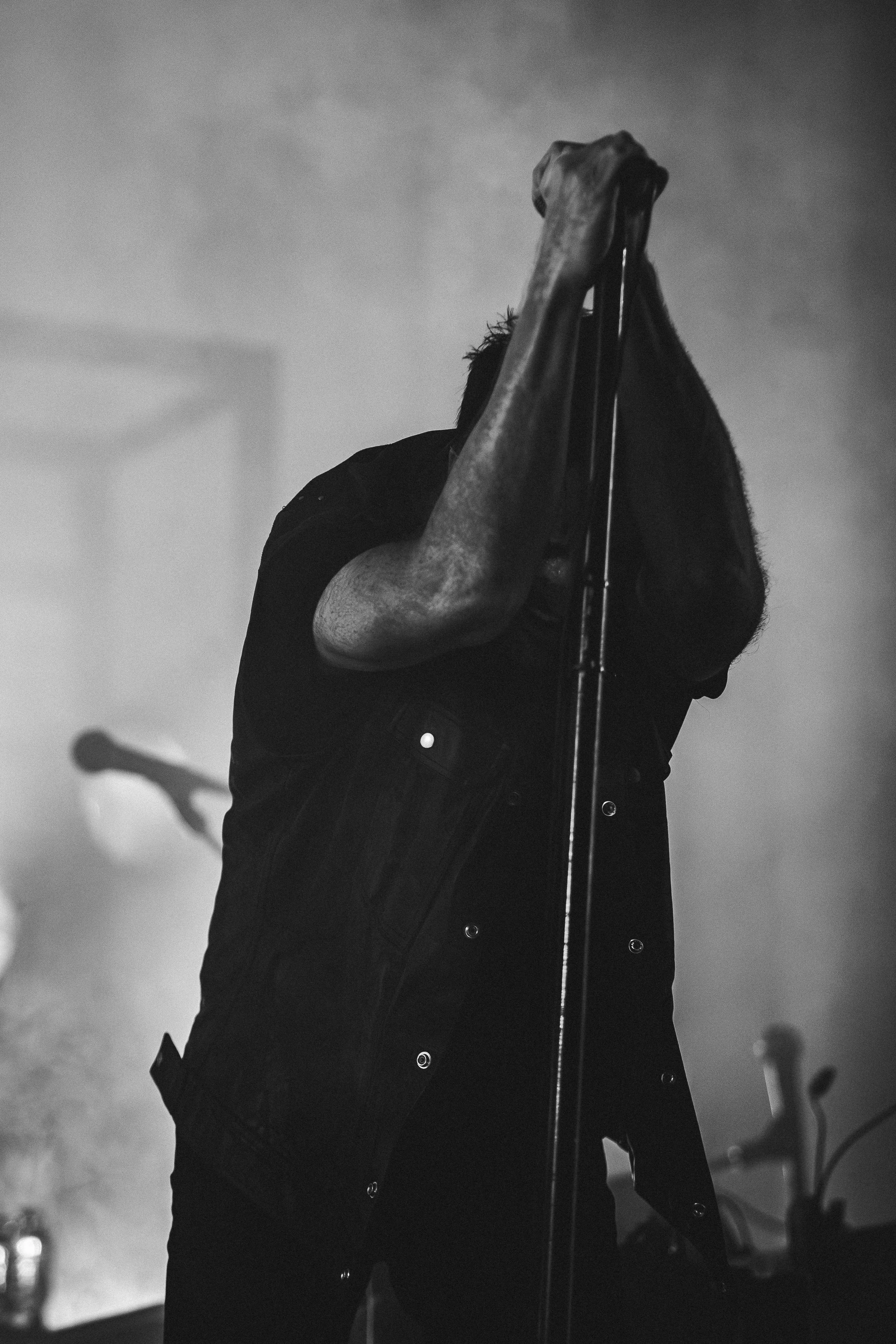 A black-and-white photo of a man holding a microphone with both hands over his face during a performance.