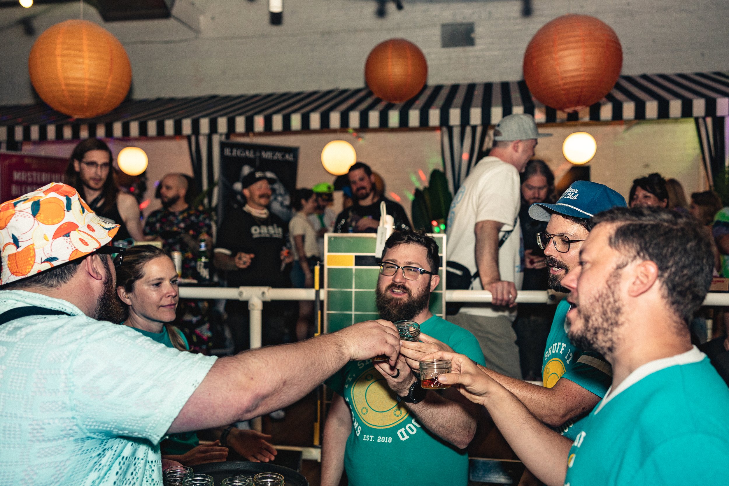 A group of friends socializing at a lively party or bar, raising glasses and toasting with drinks.