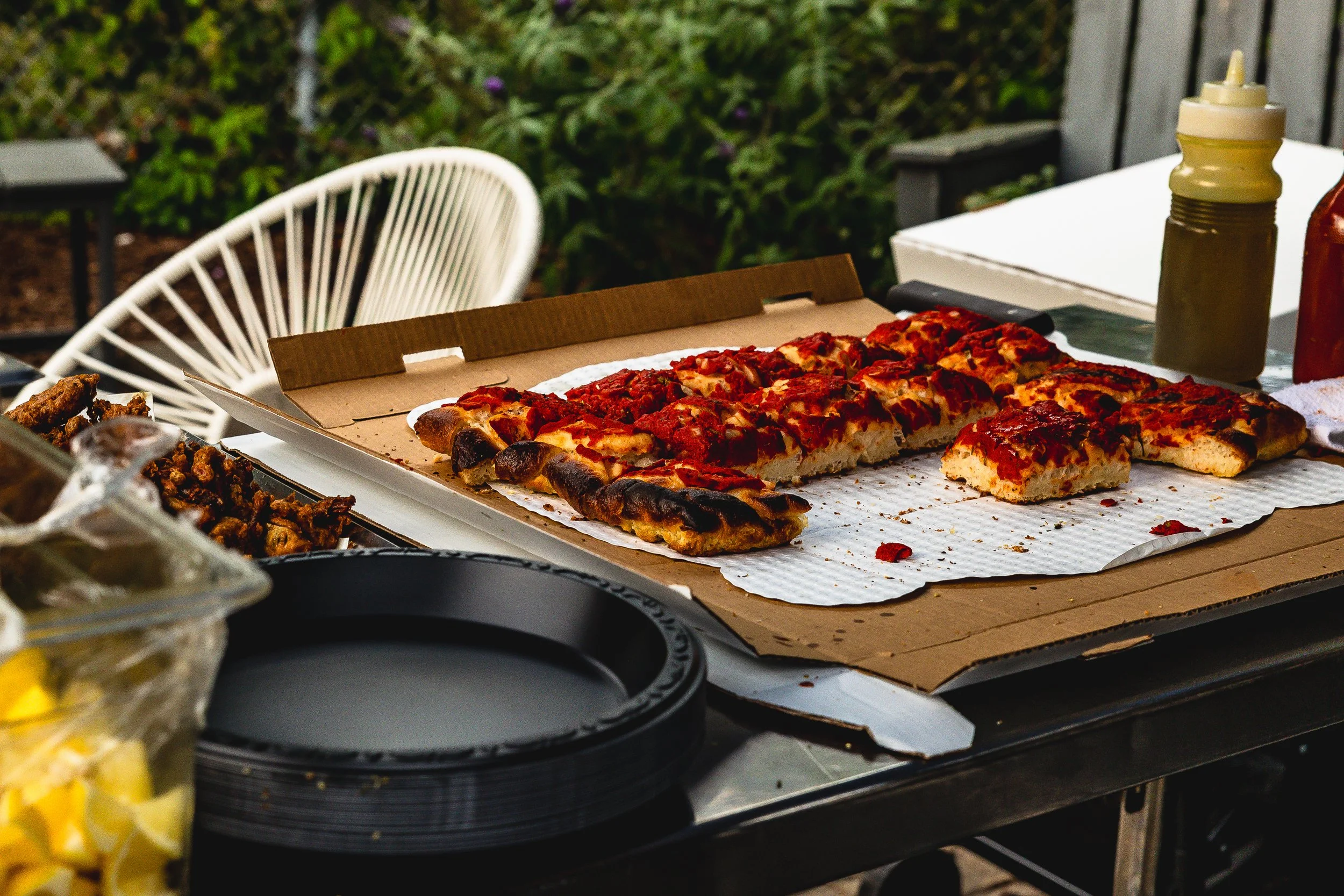 Pizza with pepperoni slices on a pizza box at outdoor gathering