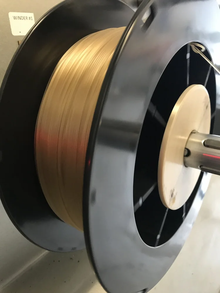 Close-up of high-temperature filament being wound onto a large black spool during production