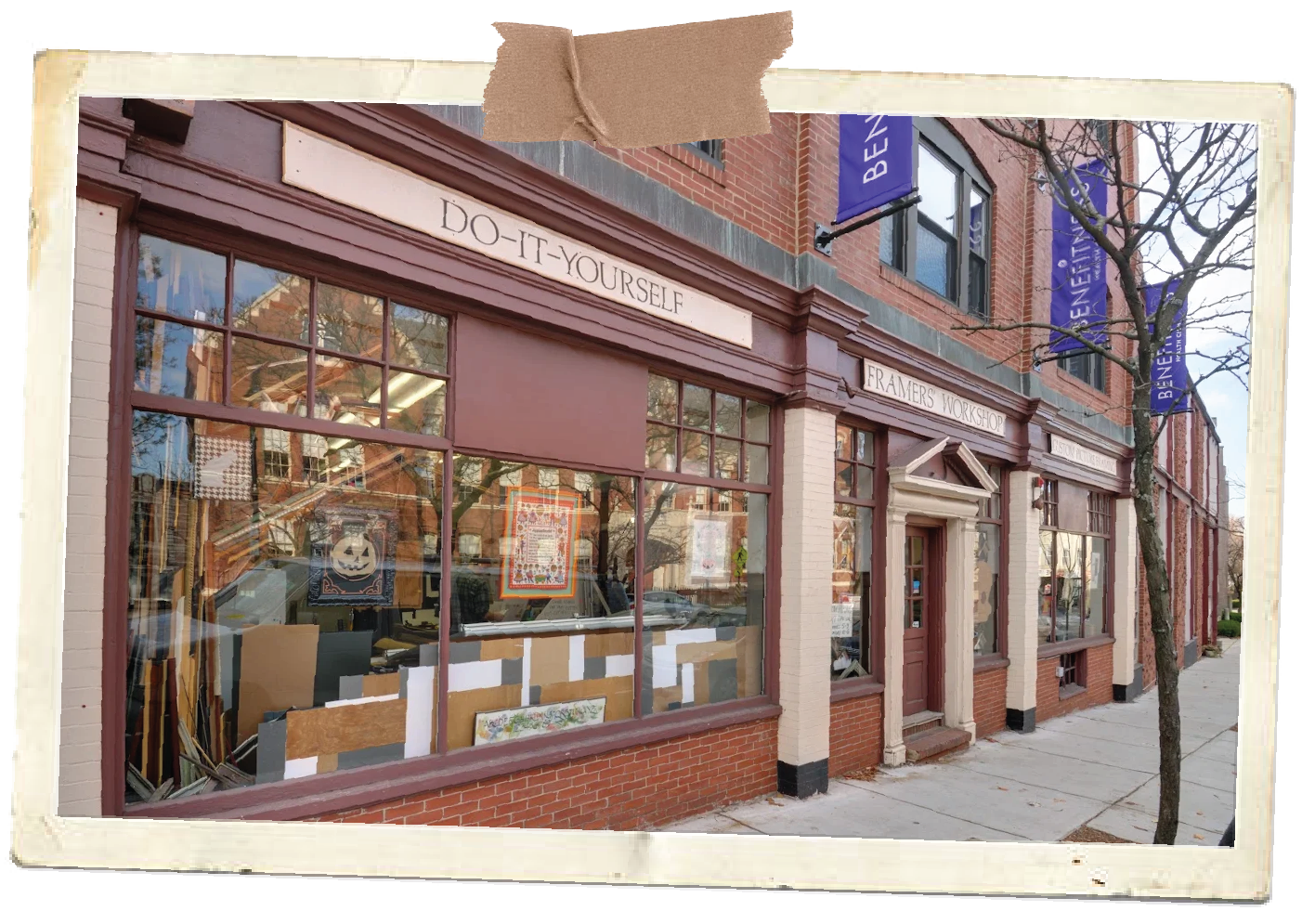 Exterior of a brick building with large display windows filled with artwork, and signs reading "DO-IT-YOURSELF" and "FRAMERS WORKSHOP," on a street with leafless trees and sidewalk.