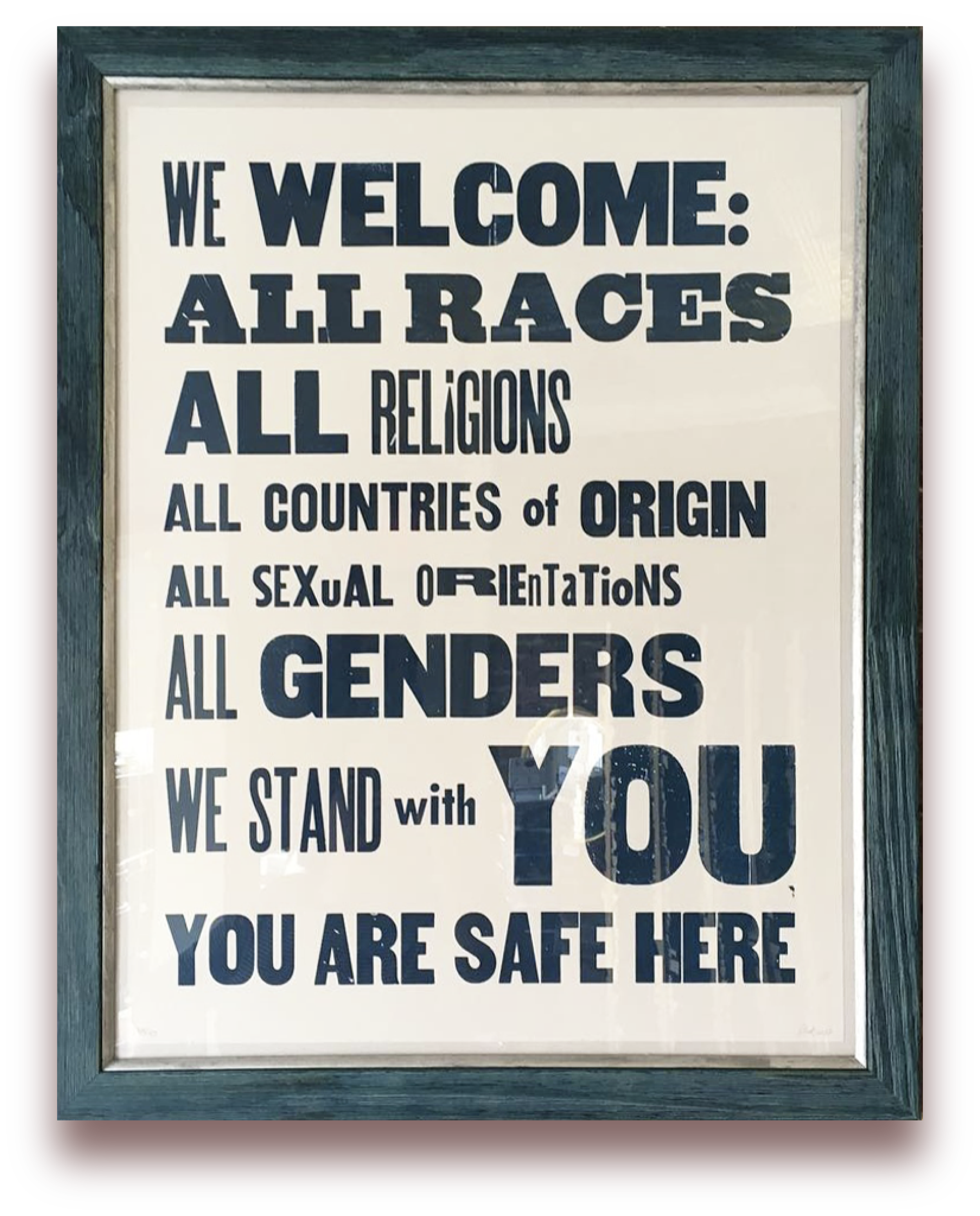 Sign with message welcoming all races, religions, countries, sexual orientations, and genders, stating 'We welcome all races, all religions, all countries of origin, all sexual orientations, all genders. We stand with you. You are safe here.'
