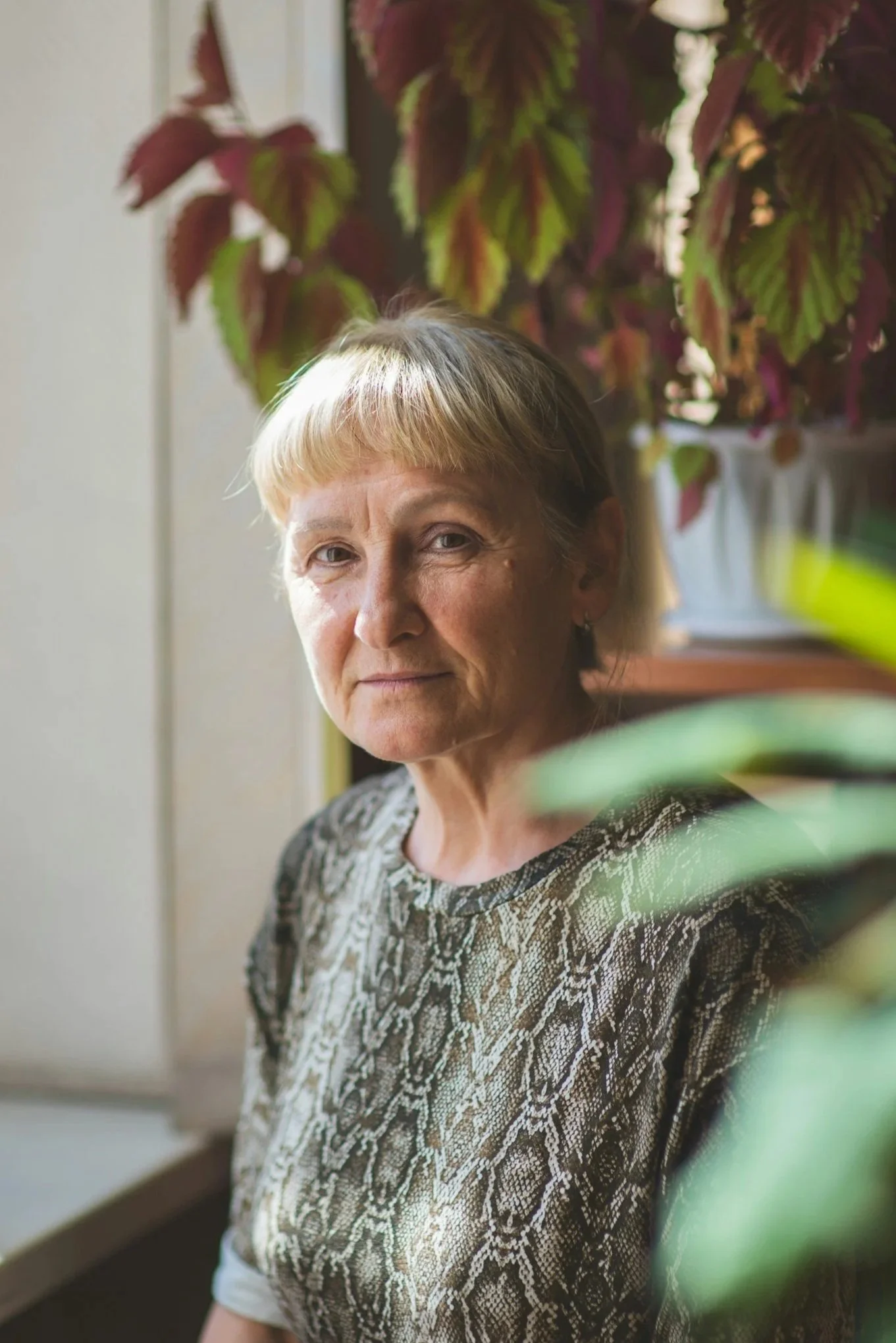 An adult woman surrounded by potted plants