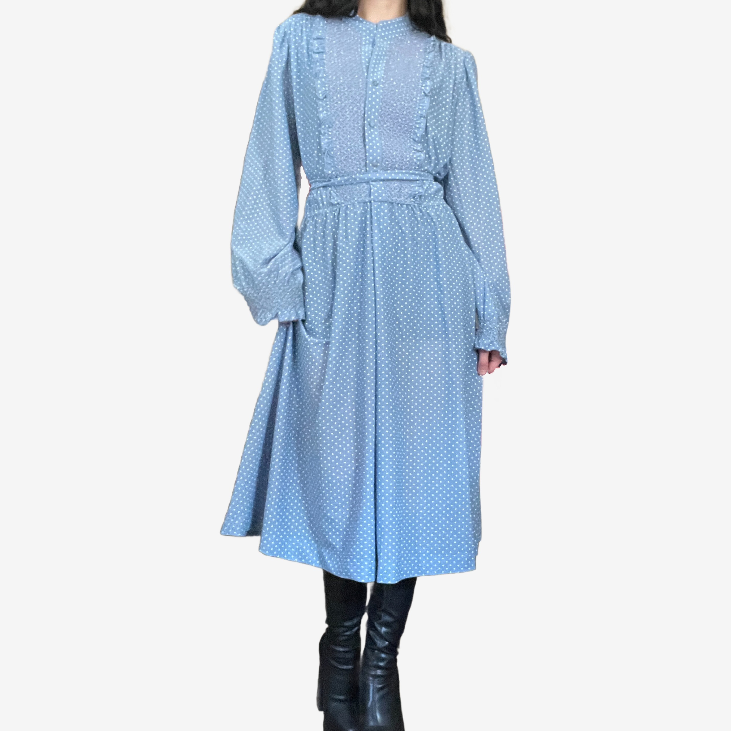 Woman in a long blue polka dot dress with black knee-high boots.