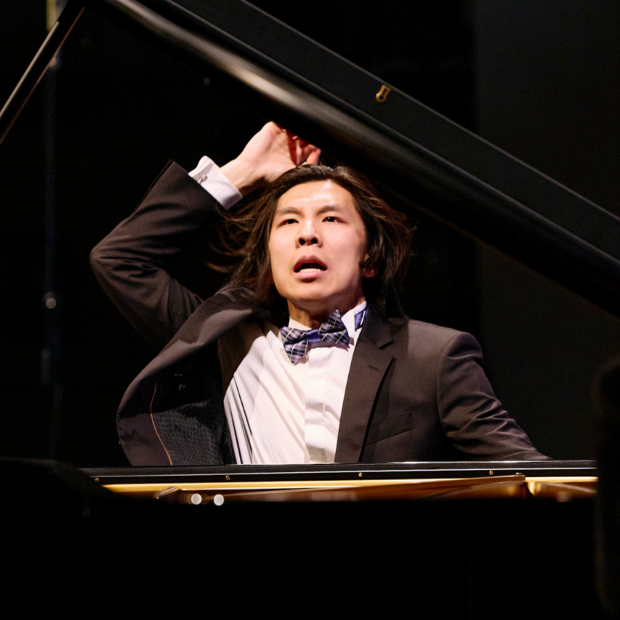 Person in a black shirt standing against a wooden background