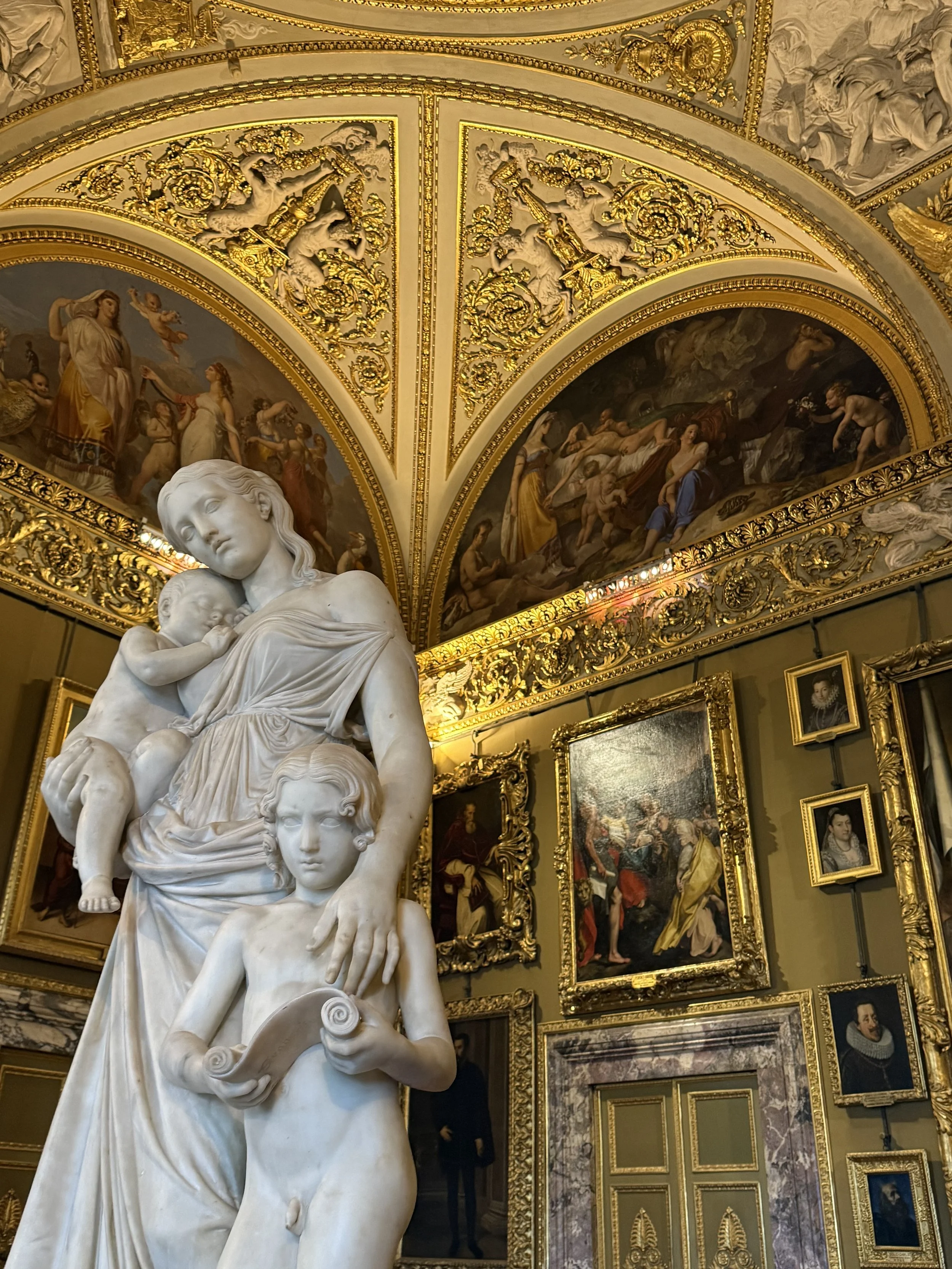 Palazzo Pitti, Florence. The Sala dell'Iliade, where the paintings are hung in tiers as the grand dukes arranged them. Lorenzo Bartolini's Carità Educatrice has stood at the centre since 1861.