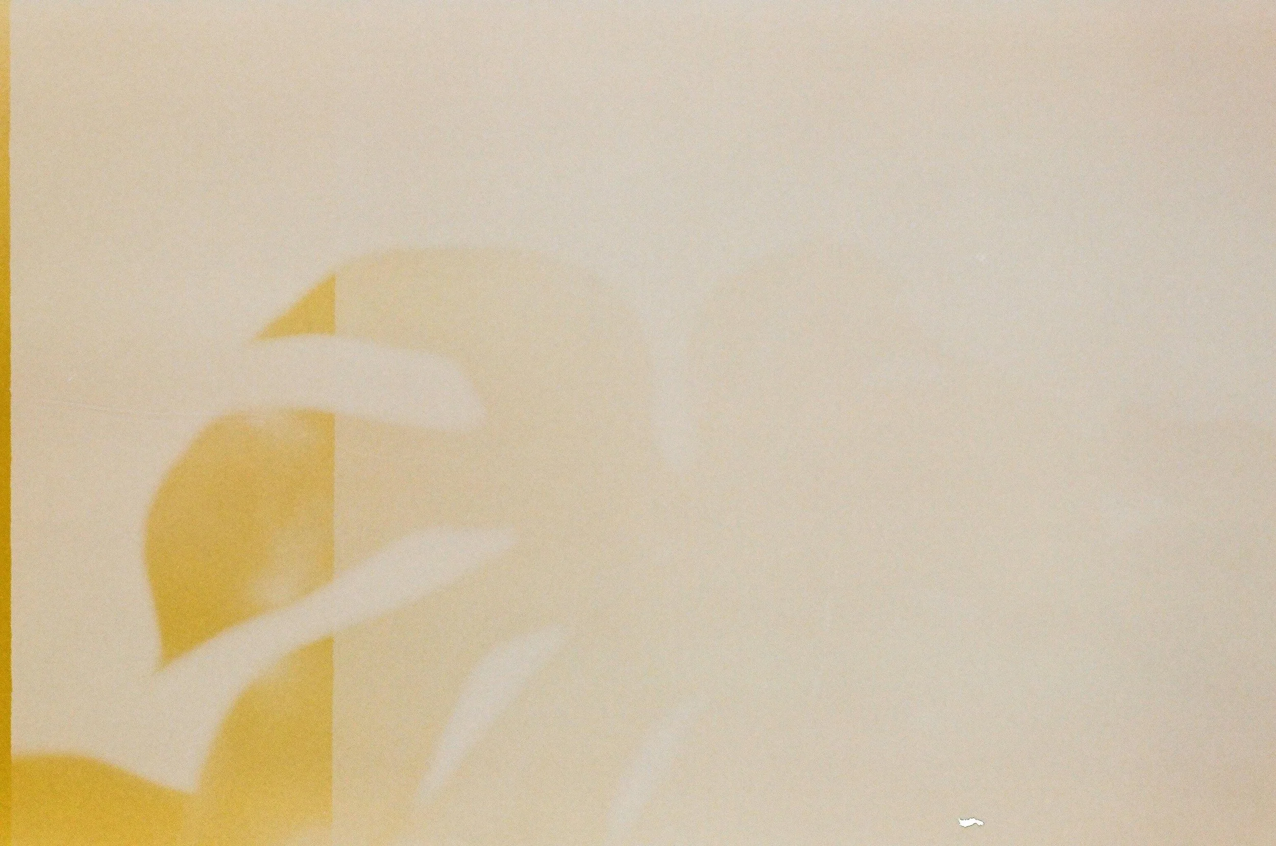 Close-up of a yellow and white paper craft with curving shapes on a beige background.