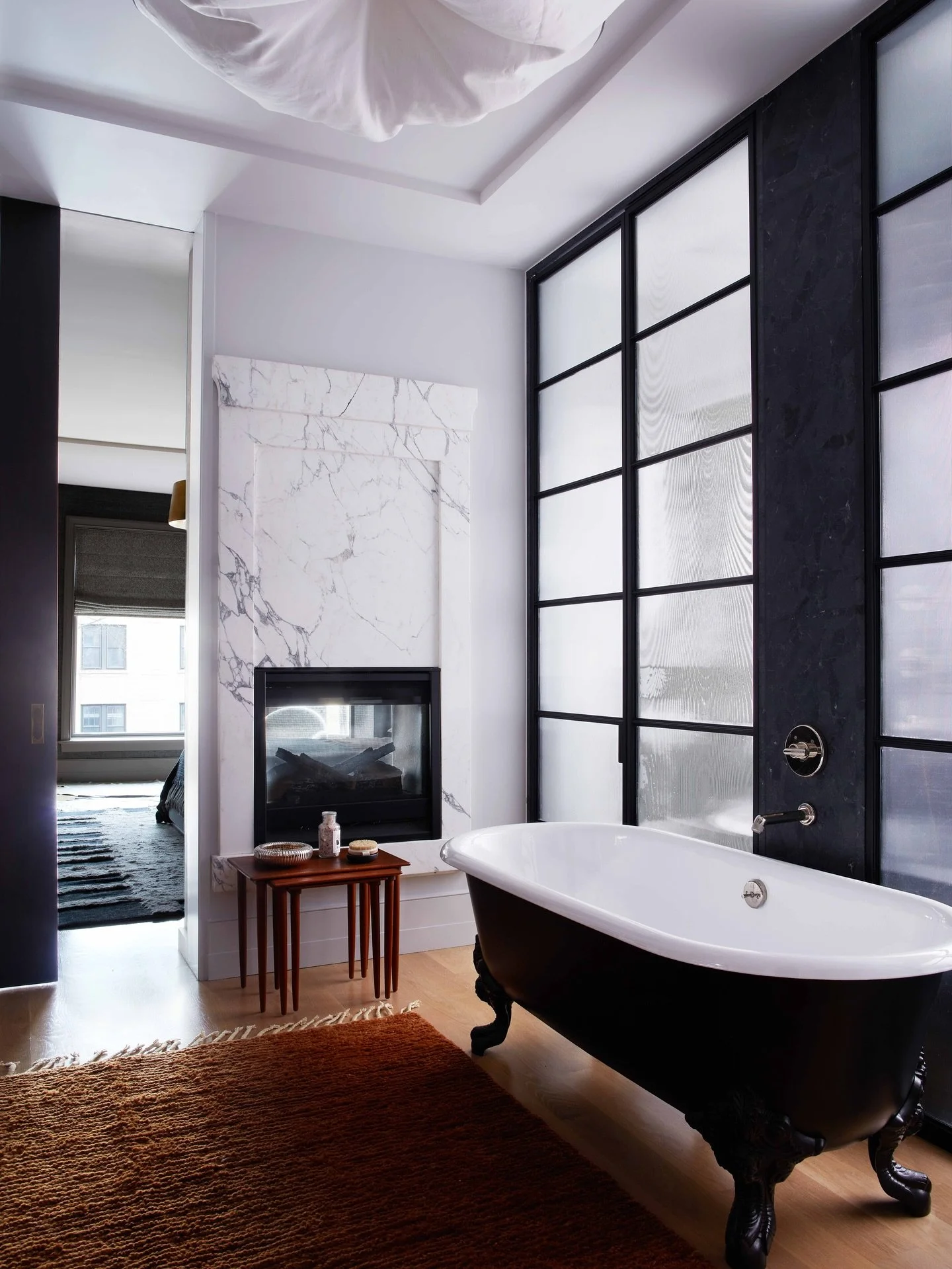 Suite / Located in a stately Wicker Park brownstone this primary suite boasts a rich material palette and layered spaces. Walnut cabinetry, a stone clad fireplace, glass and steel walls, and a claw foot tub bridge the home&rsquo;s history with its mo