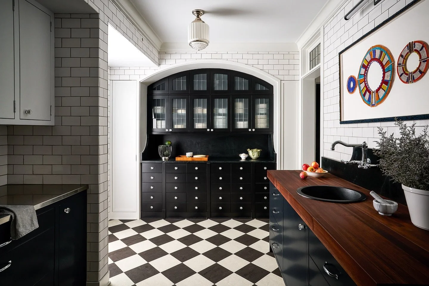 Black + White / In a home full of color this high contrast color scheme brings character reminiscent of the unit&rsquo;s 1920s architecture. Vintage light pair with custom cabinetry, tiled wall, stainless steel, stone and butcher block countertops. #