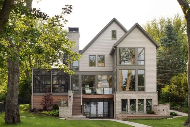 OUT NOW / Day to day the main approach to this law home is from the water side. With its large expanses of glass and stone base this elevation is both contemporary and evokes a more classic cottage. To one side of the home is an oversized screened po