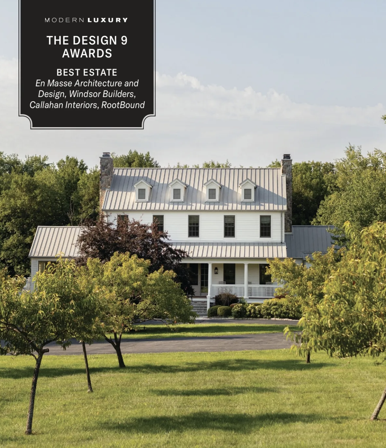 A large white house with a metal roof, surrounded by a green lawn and trees, with a black award label in the top left corner.