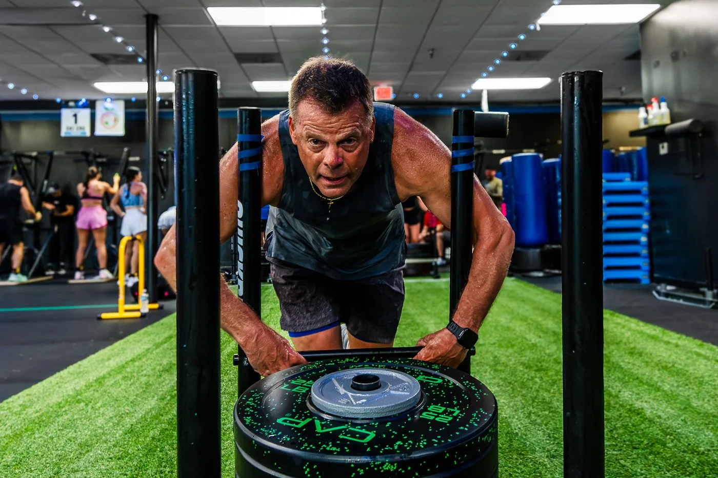 Athlete showing fatigue during a sled push at NLXF's Hyrox Sim event, Des Moines