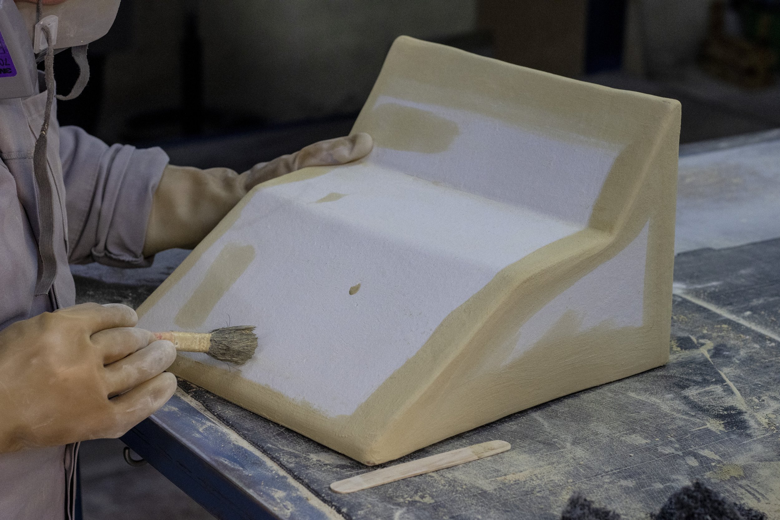 Persona pintando una escultura de yeso con un pincel en un taller.