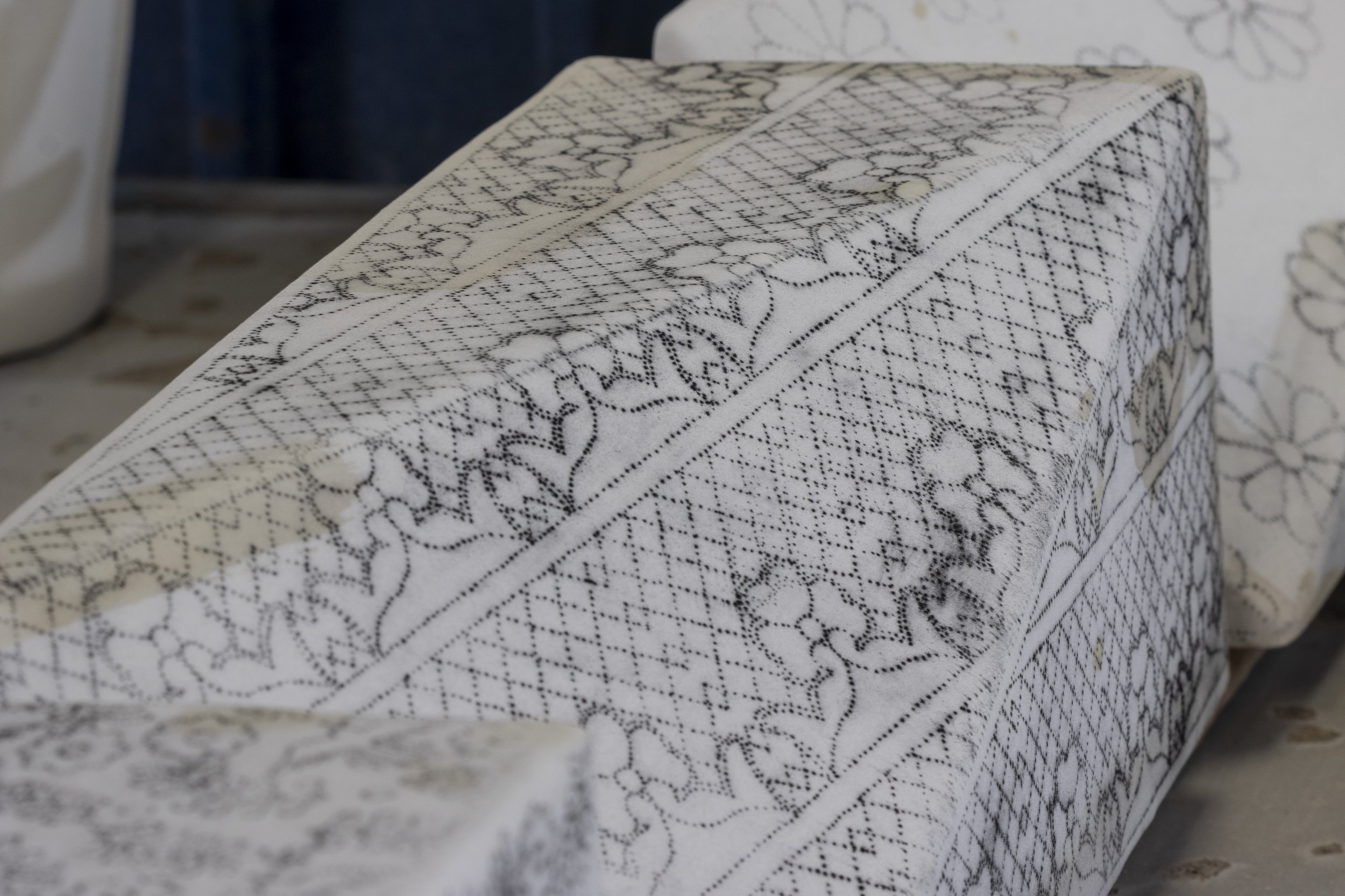 Una caja rectangular cubierta con tela de encaje blanco con detalles en negro.