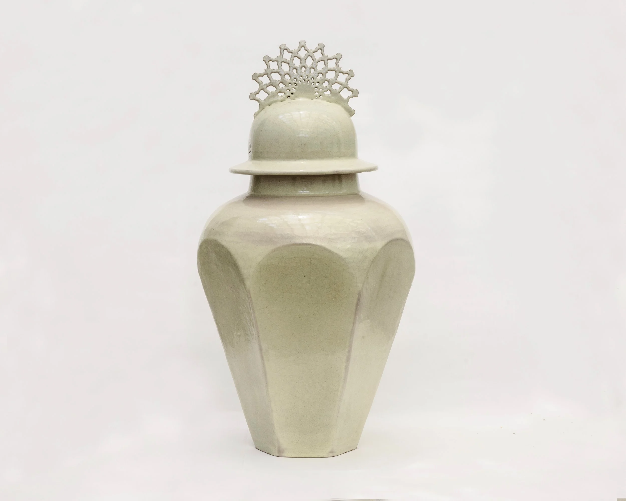 Jarrón decorativo blanco con cavidades en la parte superior y una figura decorativa en forma de copo de nieve en la parte superior