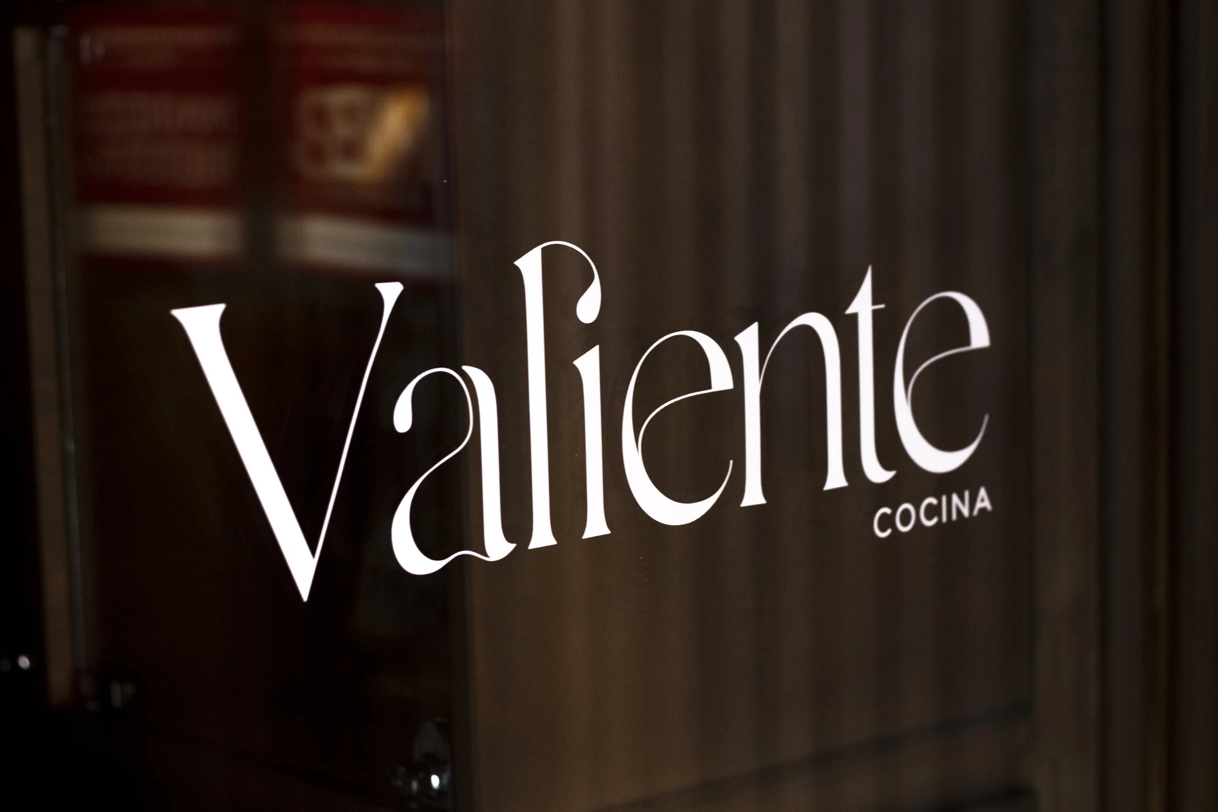 Cartel que dice 'Valiente Cocina' en letras blancas sobre un fondo de madera.