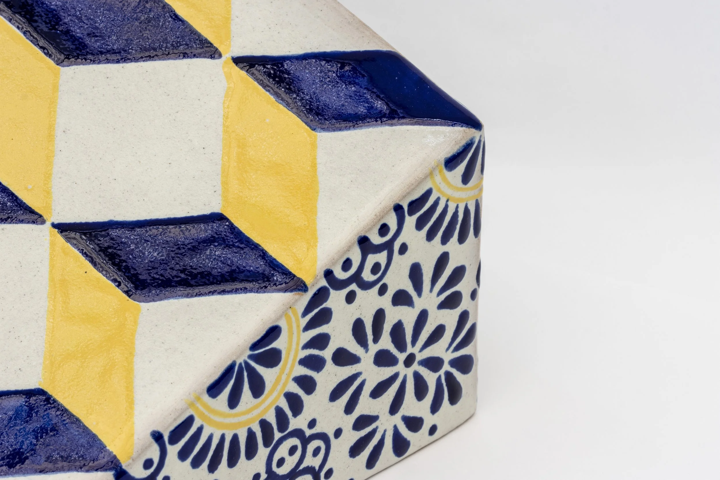 Cerámica decorativa con patrones geométricos en colores amarillo, azul y blanco, con detalles florales y abstractos.