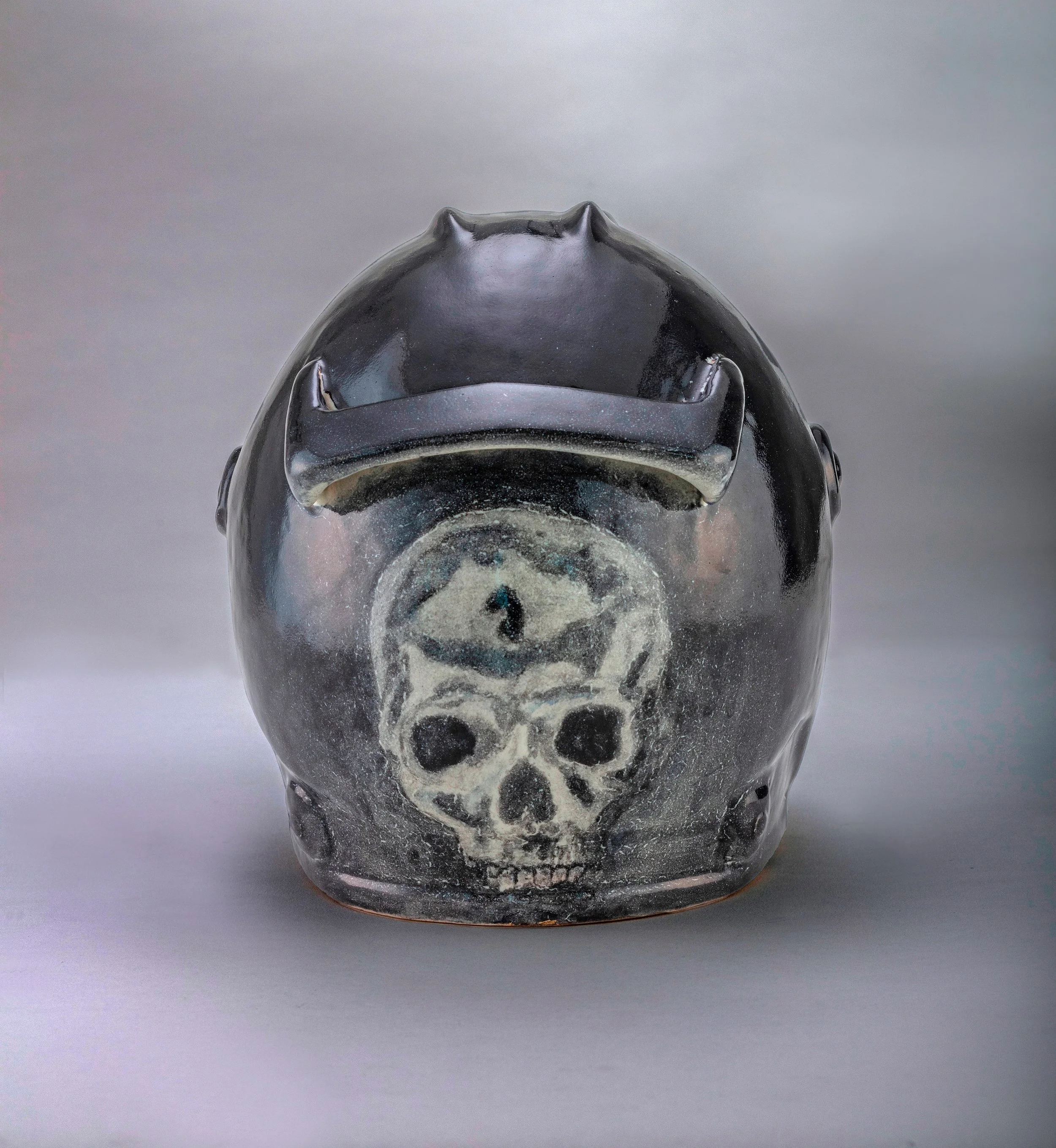 Vas de cerámica negra con pintura de calavera en la parte frontal
