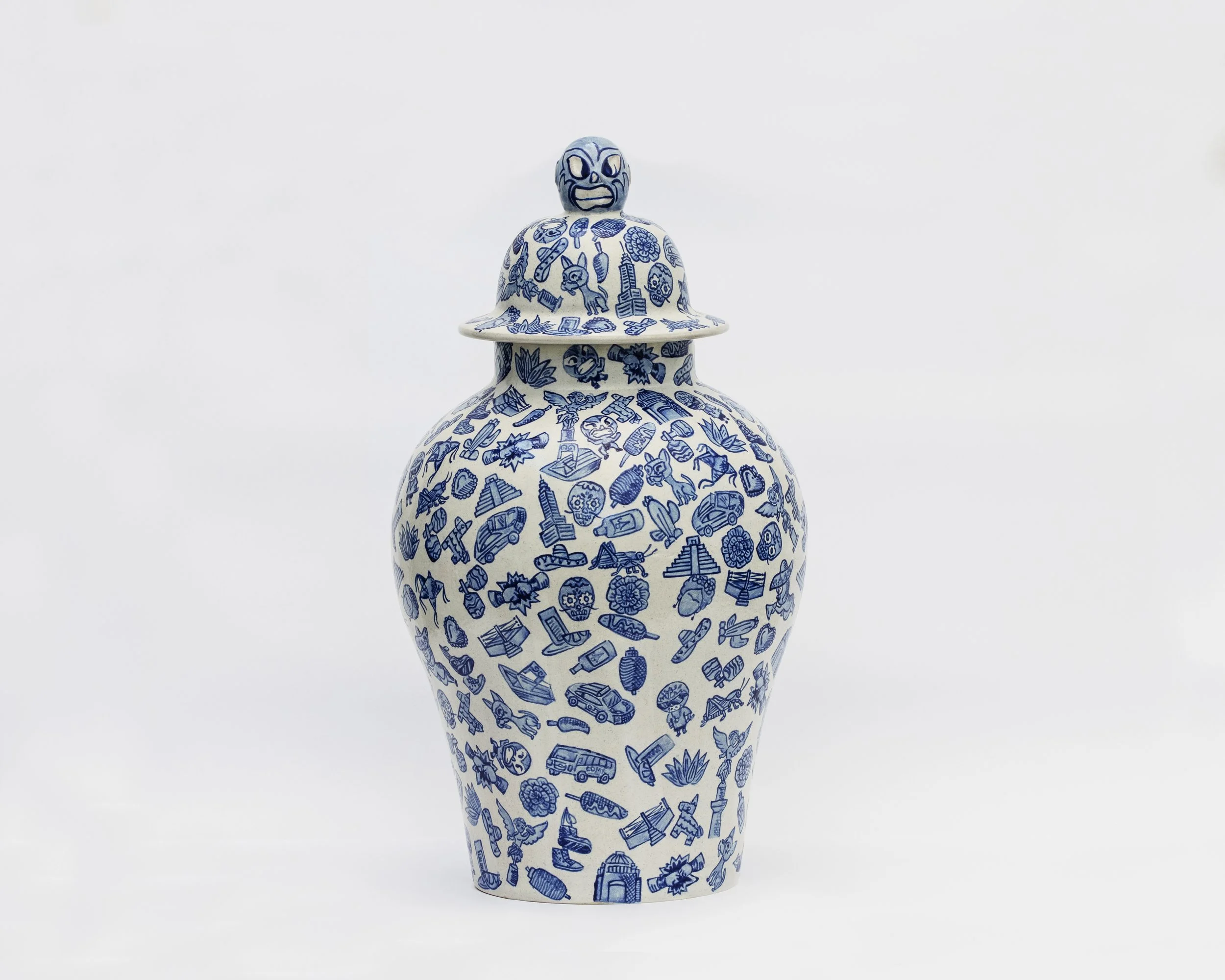 Jarrón decorativo de cerámica con diseño en azul y blanco, con una tapa que tiene una figura de rostro con expresión de sorpresa.