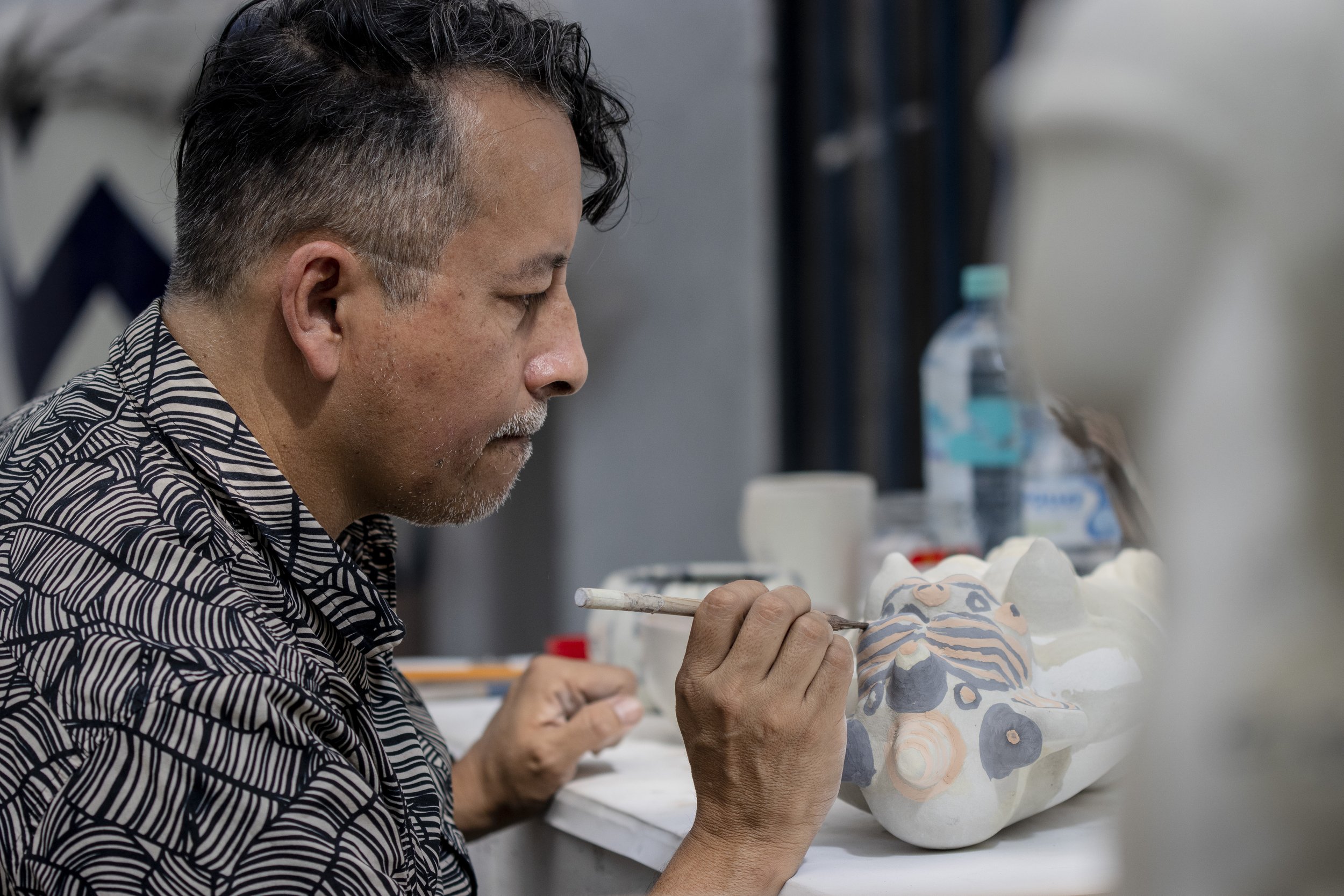 Hombre pintando una máscara de cerámica en un taller de arte.