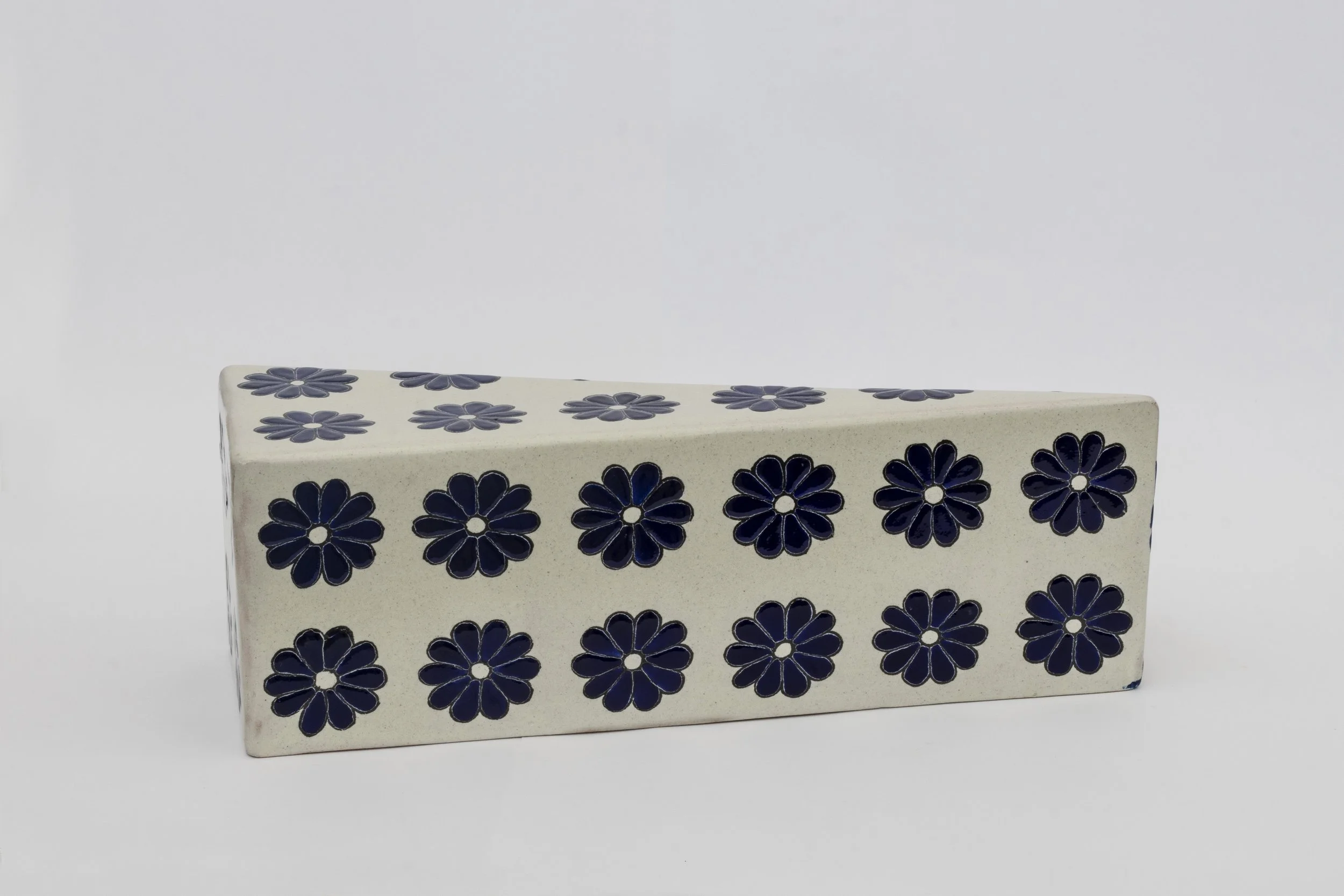 Bloques de cerámica decorativos con patrón de flores azules sobre fondo beige.