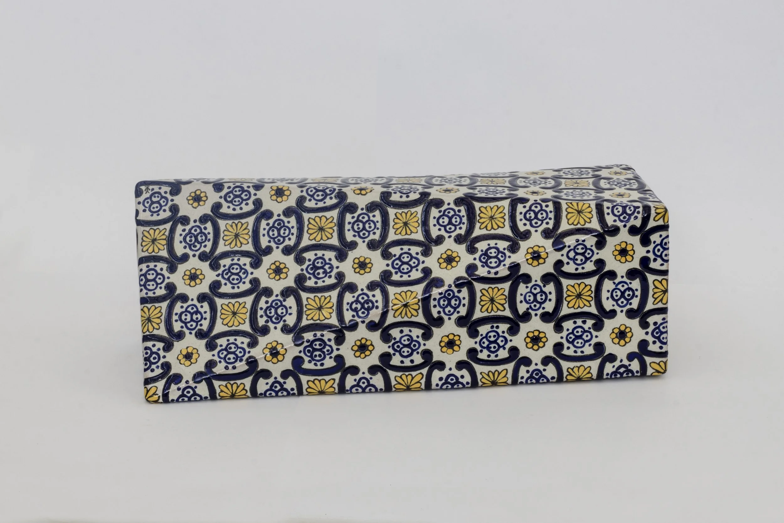 Caja rectangular decorada con patrón de flores y diseños en colores azul, amarillo y blanco.