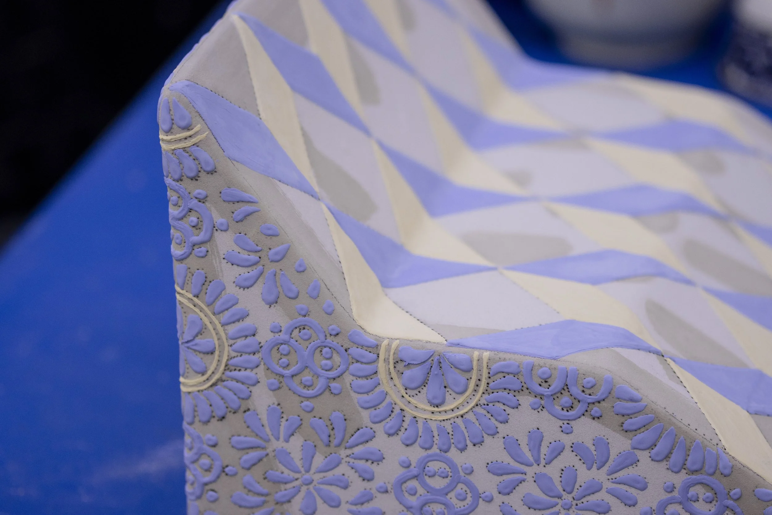 Primer plano de una pieza de cerámica decorada con patrones en azul y beige.