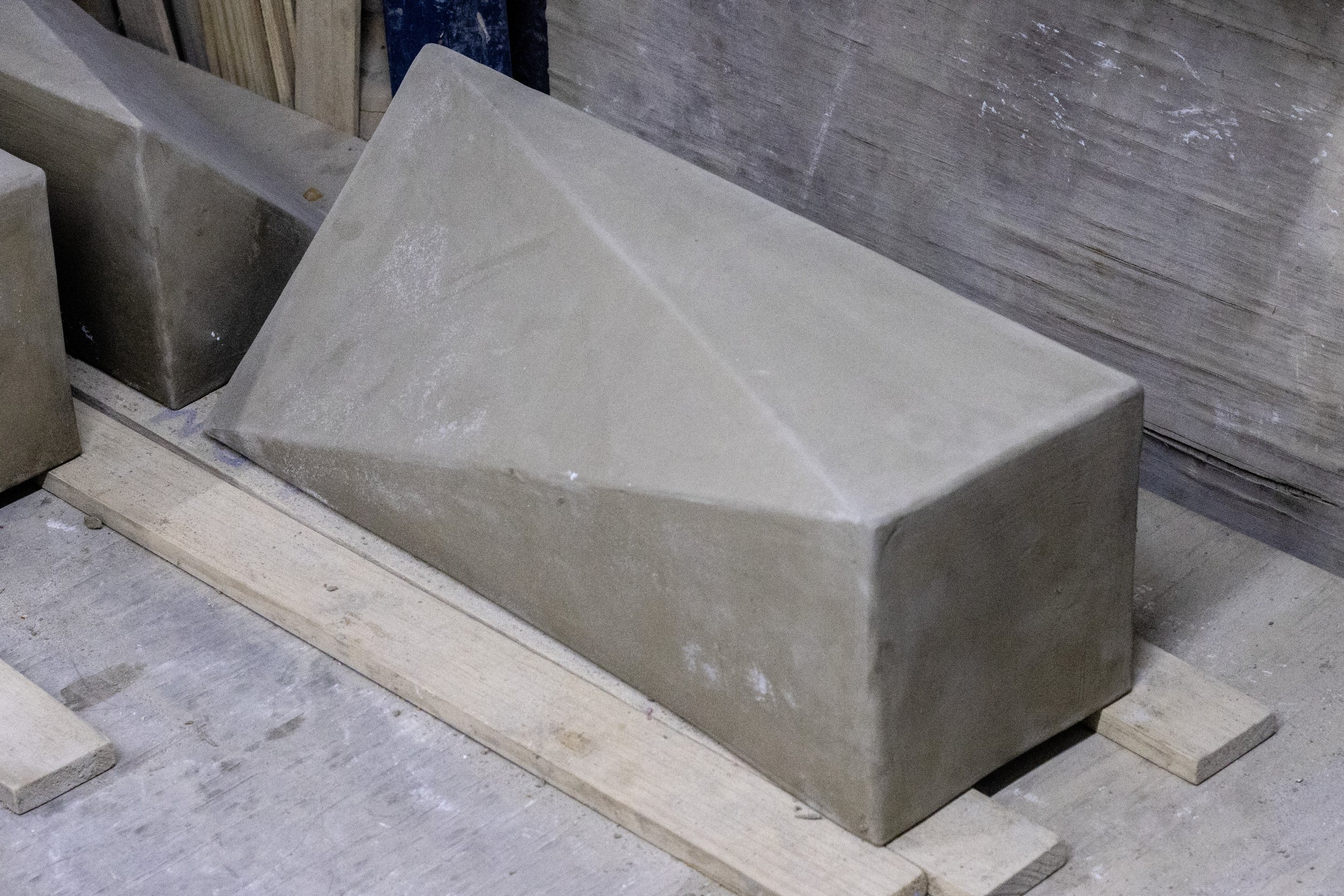 Lámina de piedra en una superficie de construcción, con otros bloques de piedra y madera a su alrededor.