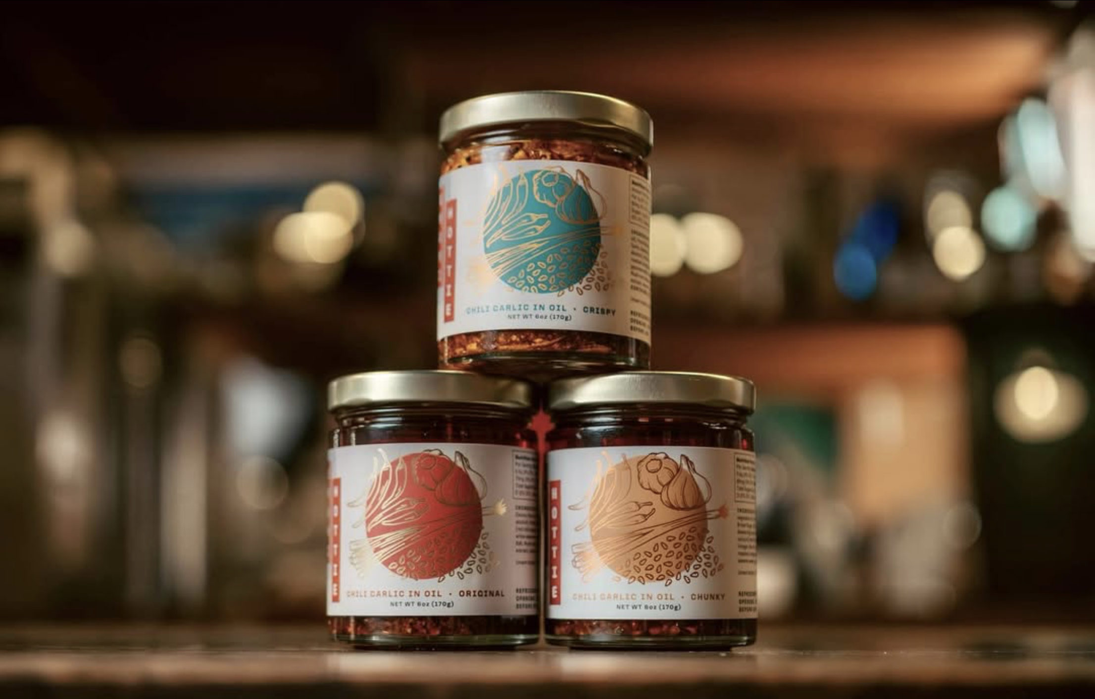 A stack of Umami Hottie chili oil jars with two jars on the bottom and one on top.