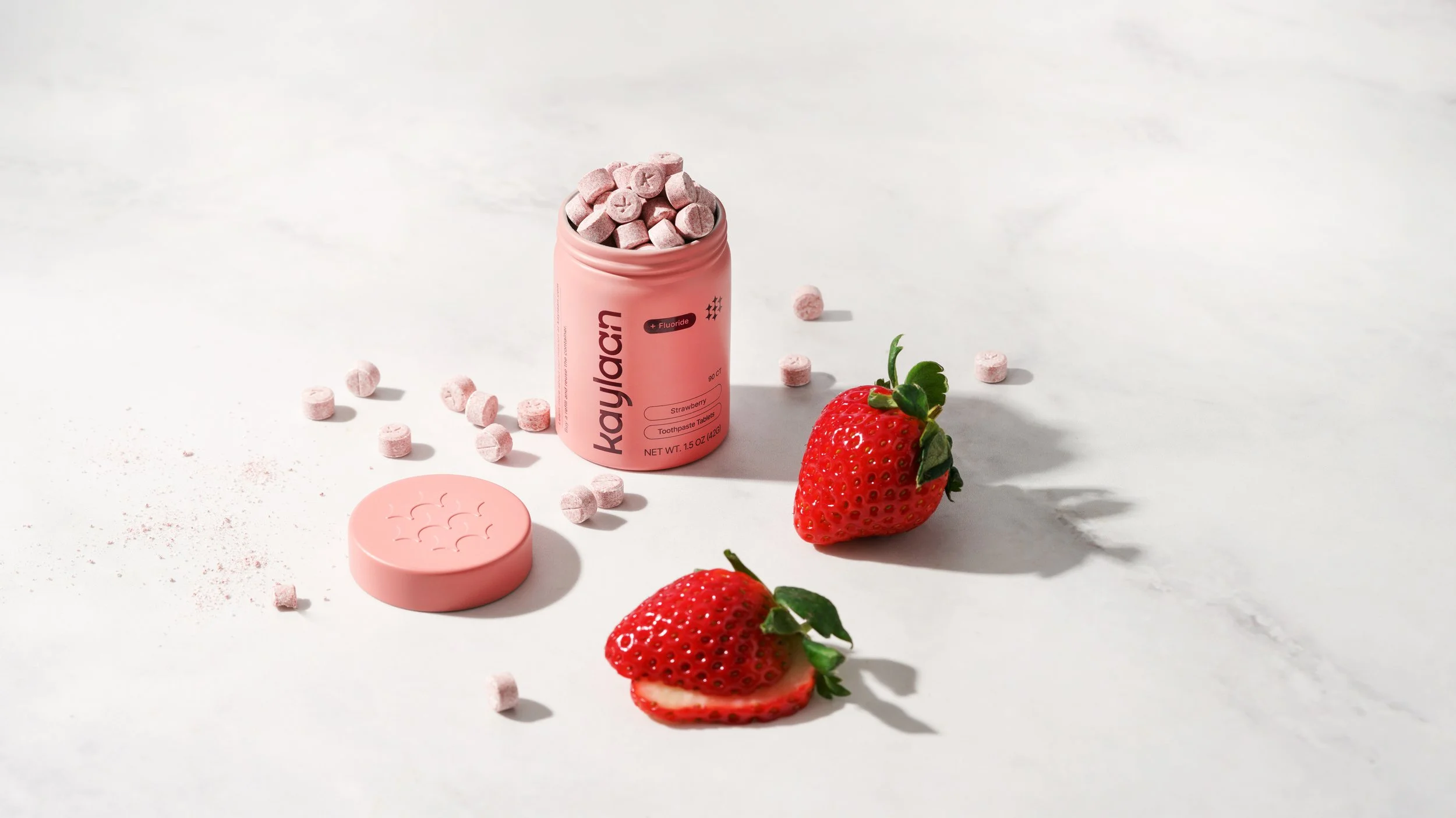 Kaylaan toothpaste tablets in a pink tin with tablets and a lid and strawberries