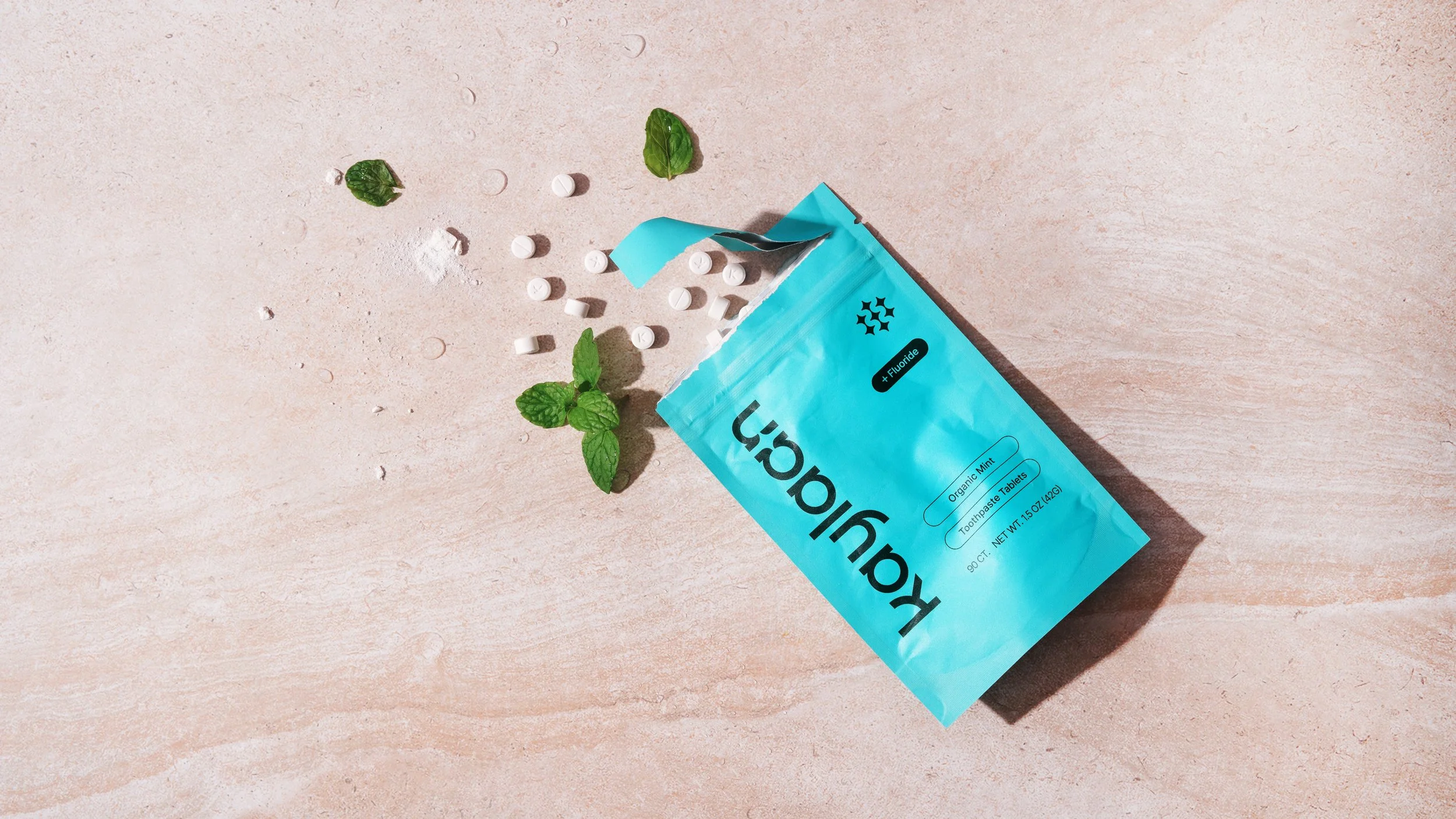 Kaylaan blue mint flavored toothpaste tablets refill pouch with tablets and mint leaves around