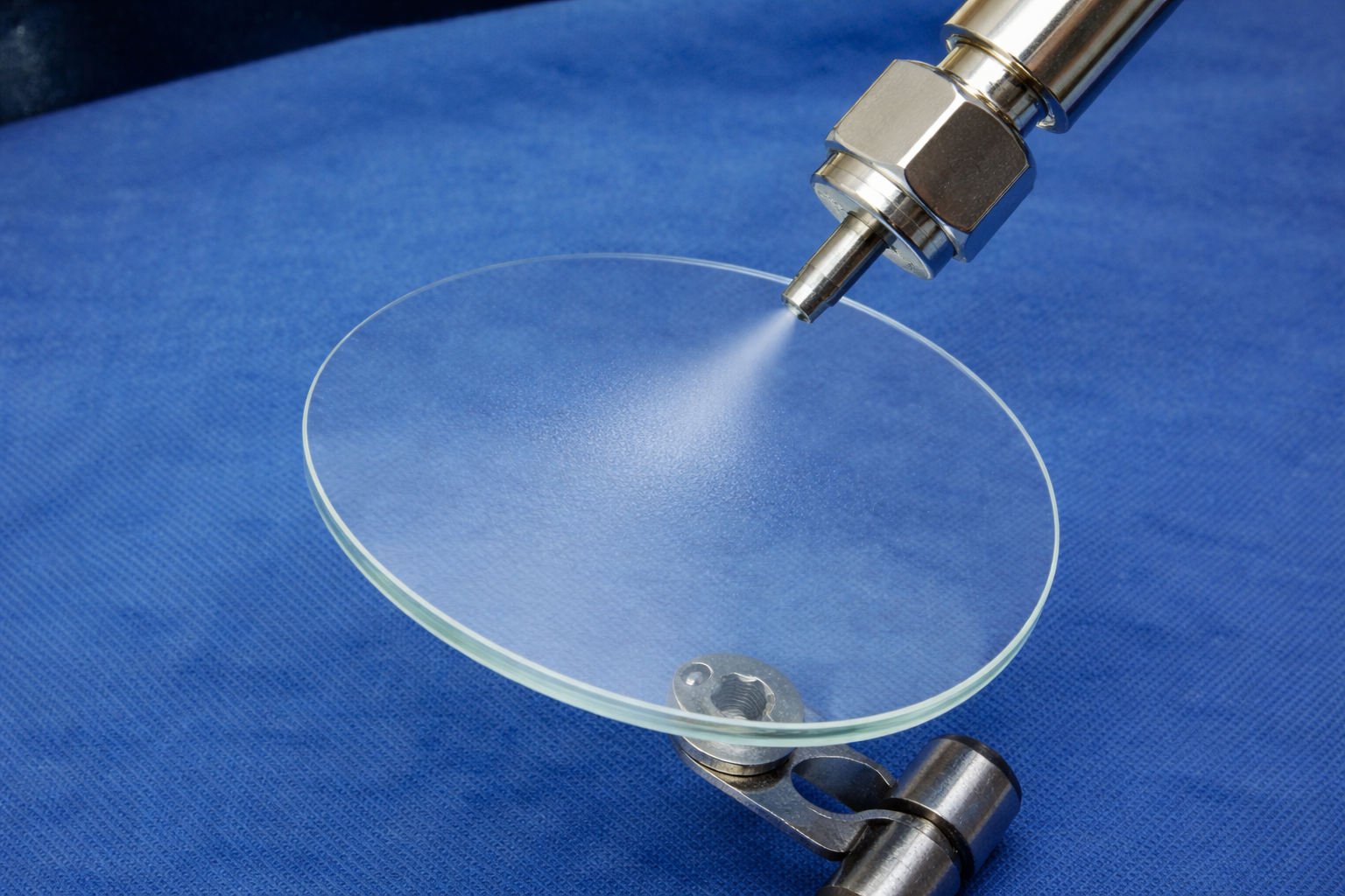 CO₂ snow spray cleaning process removing particles from a precision optical glass lens, a dry, solvent-free method used for contamination removal in optics, semiconductor, aerospace, and high-precision manufacturing.